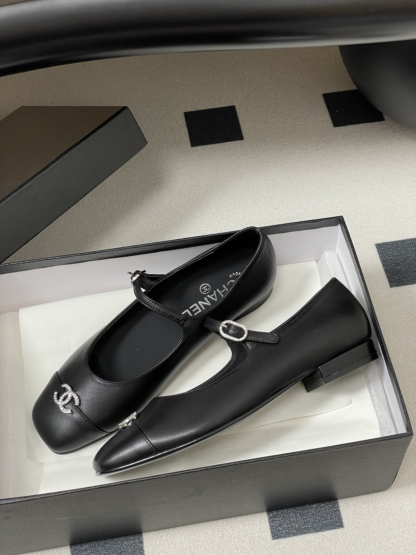 A pair of black leather Chanel Mary Jane flats featuring crystal-embellished CC logos on the toes and crystal buckles on the straps. - Hình 4