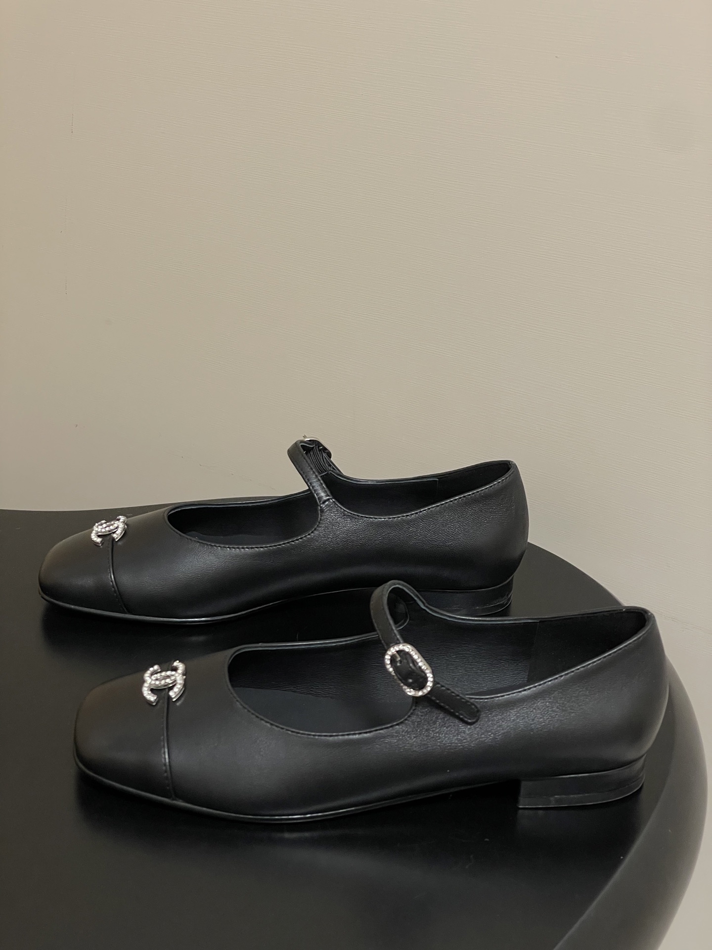 A pair of black leather Chanel Mary Jane flats featuring crystal-embellished CC logos on the toes and crystal buckles on the straps. - Hình 3