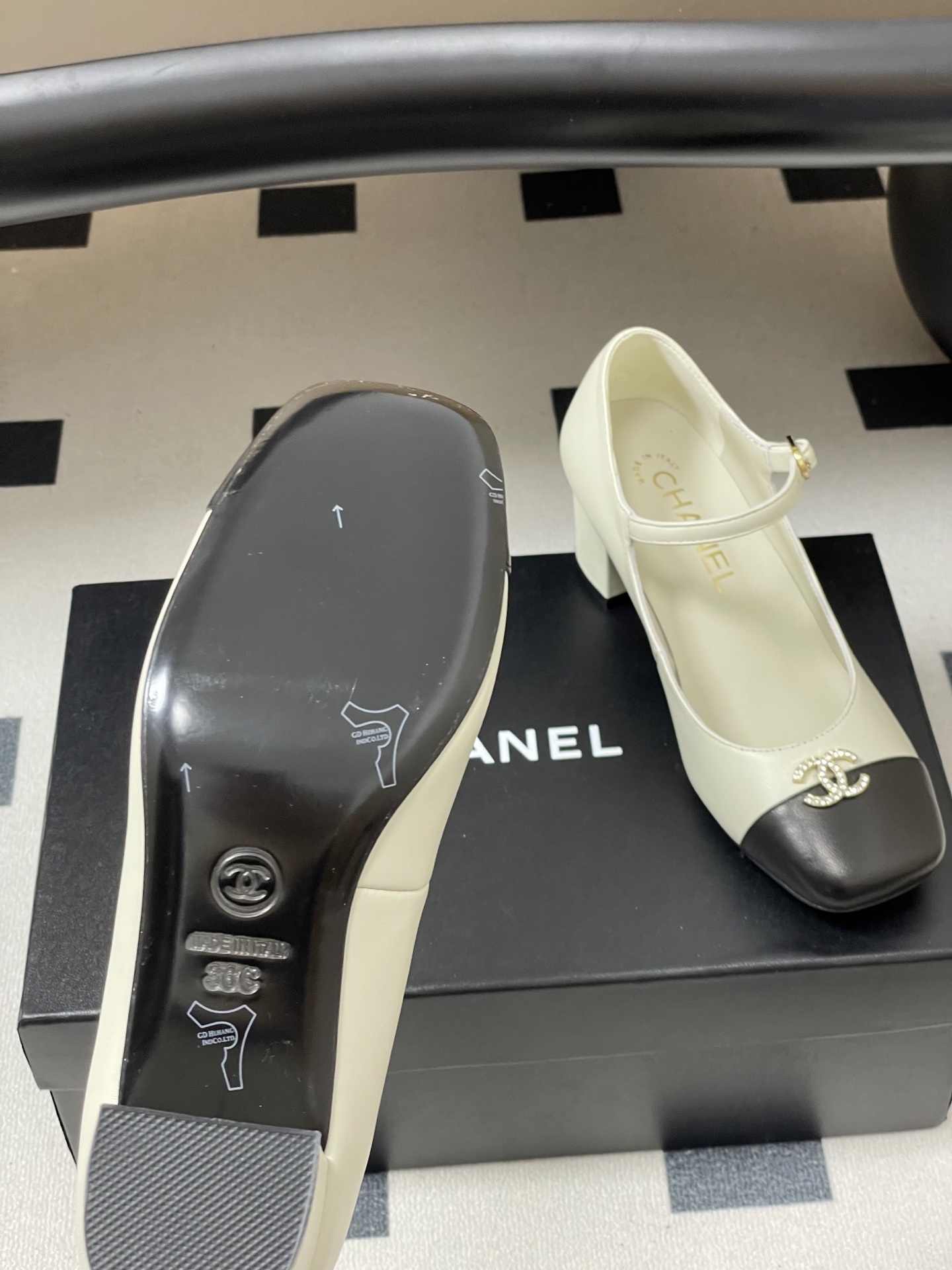 A pair of cream and black two-tone Mary Jane block heels featuring a crystal-embellished logo on the toe cap. - Hình 8