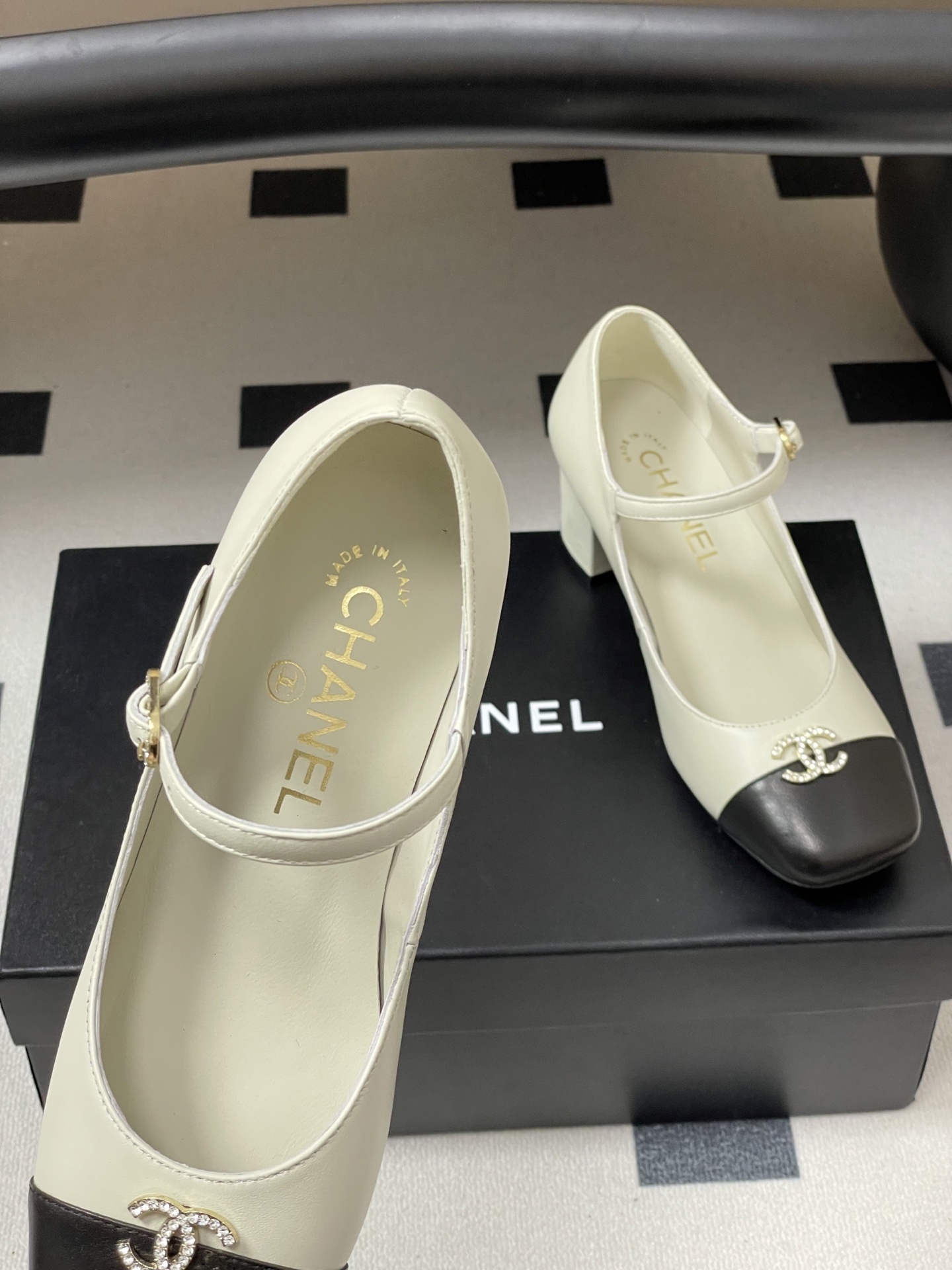 A pair of cream and black two-tone Mary Jane block heels featuring a crystal-embellished logo on the toe cap. - Hình 7