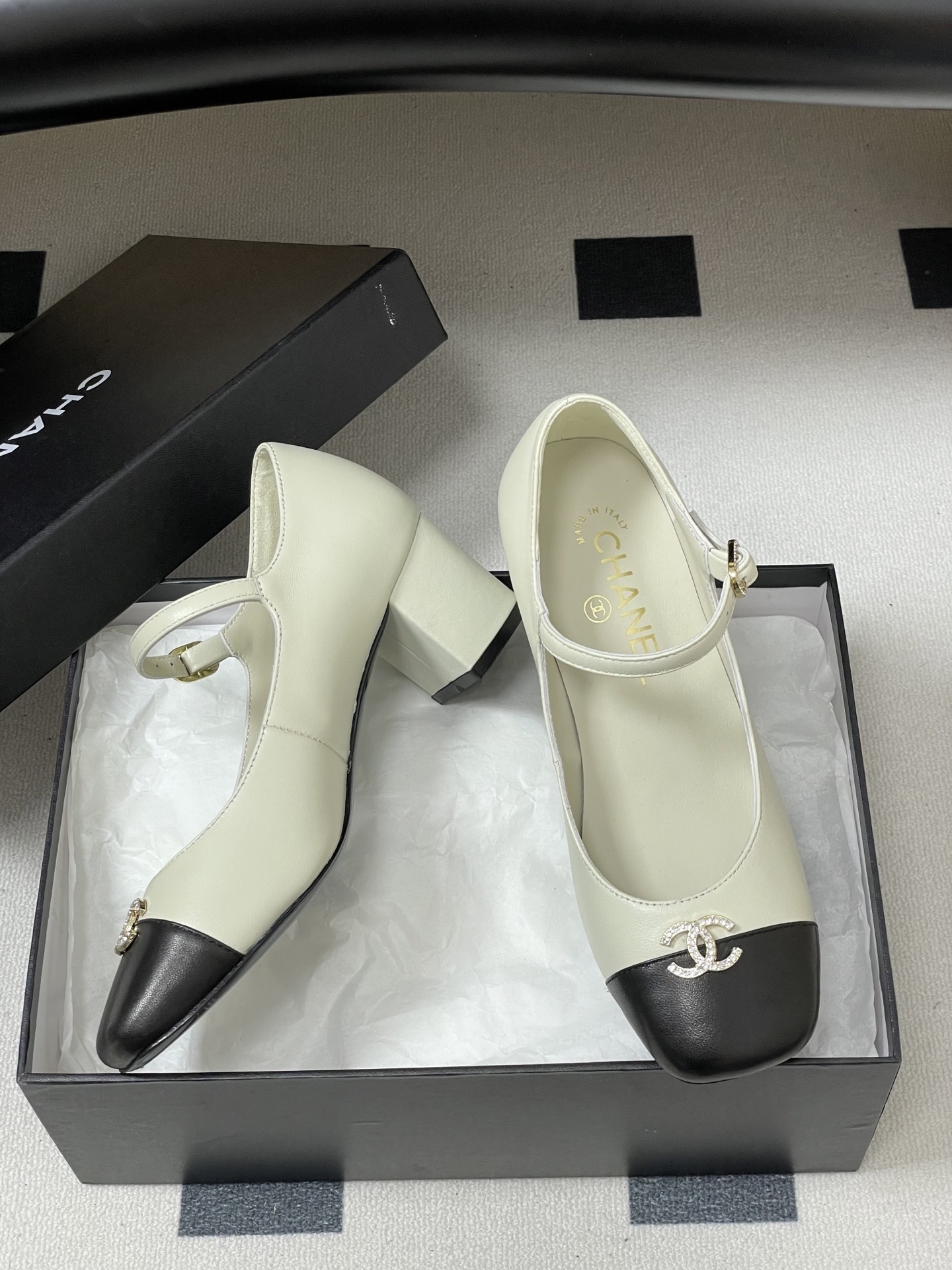 A pair of cream and black two-tone Mary Jane block heels featuring a crystal-embellished logo on the toe cap. - Hình 6