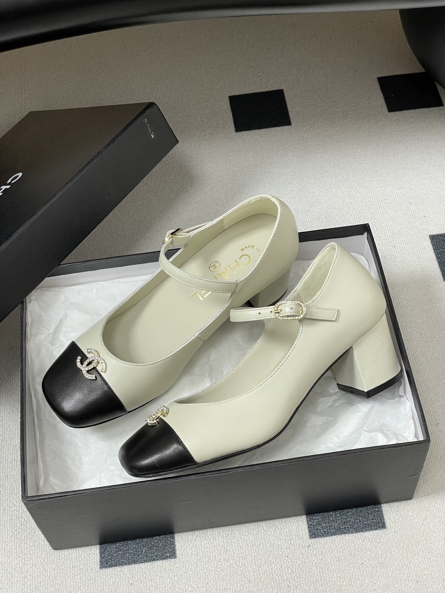 A pair of cream and black two-tone Mary Jane block heels featuring a crystal-embellished logo on the toe cap. - Hình 4