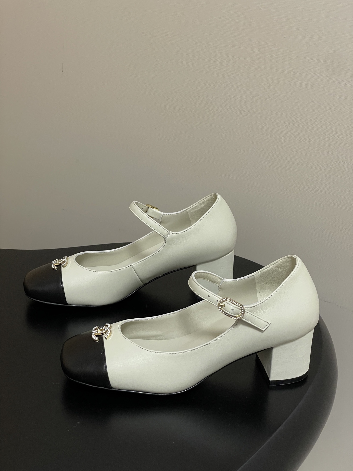 A pair of cream and black two-tone Mary Jane block heels featuring a crystal-embellished logo on the toe cap. - Hình 3