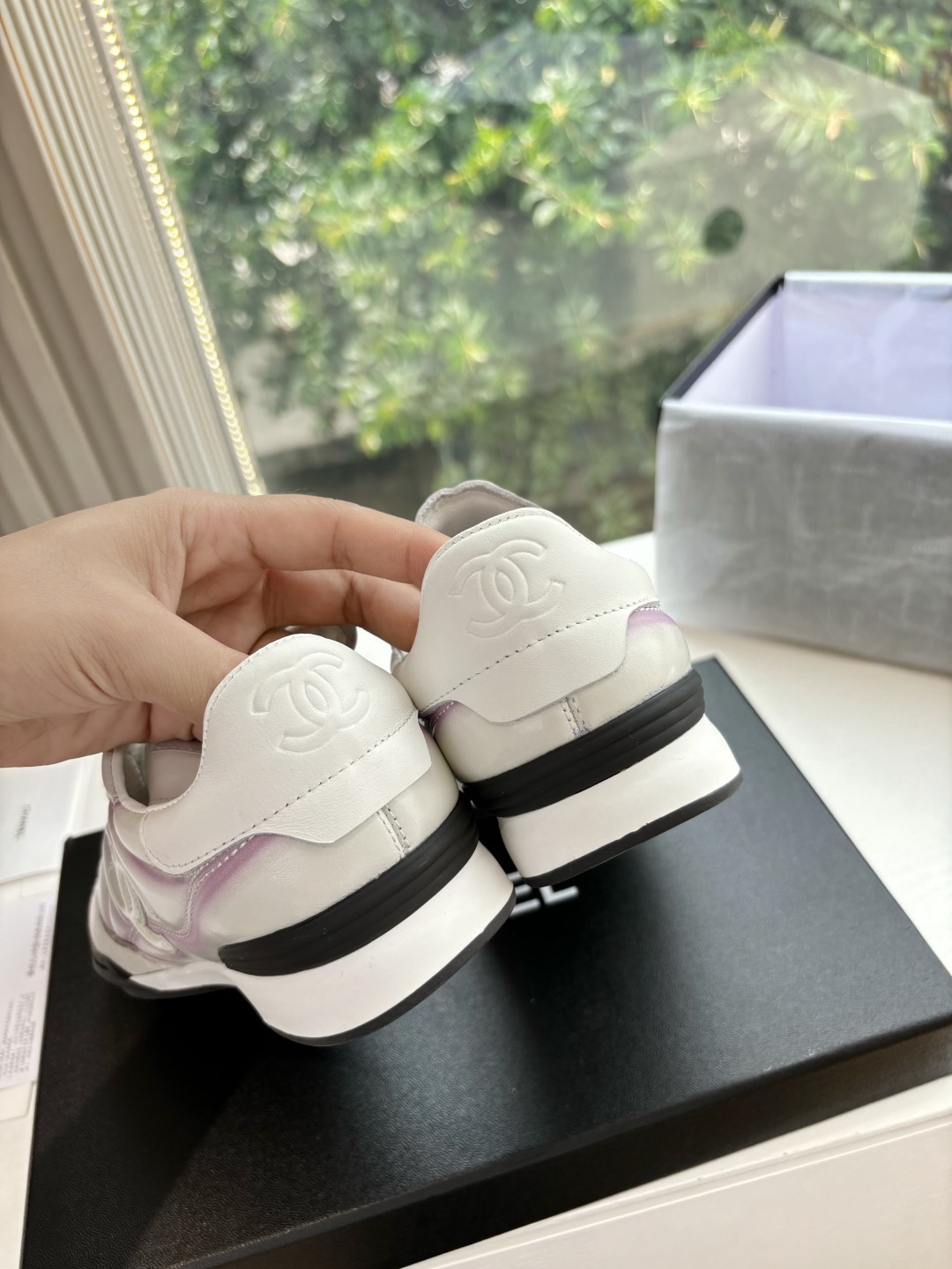 A pair of Chanel white and purple quilted leather sneakers with CC logo displayed in a box - Hình 9