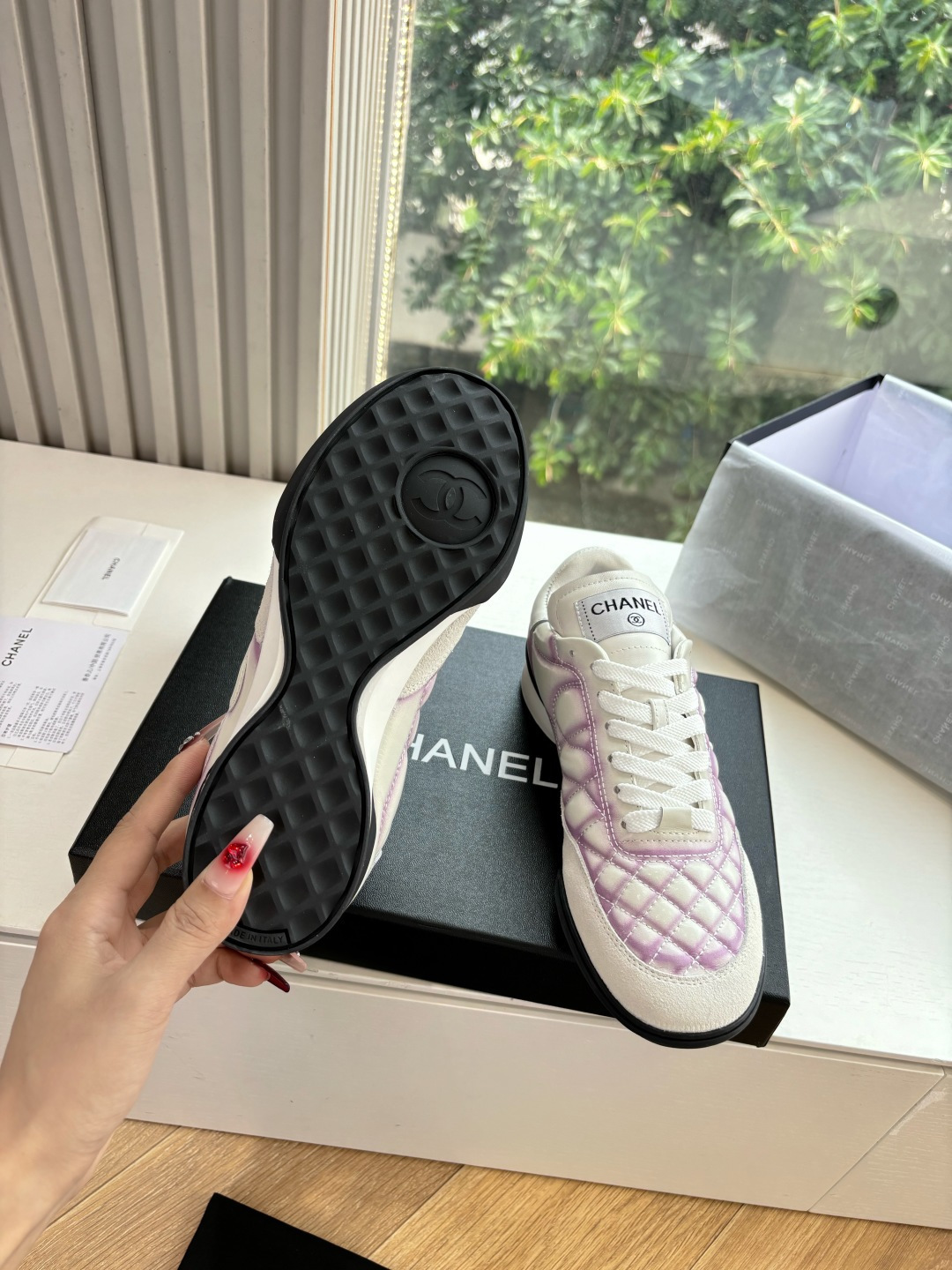 A pair of Chanel white and purple quilted leather sneakers with CC logo displayed in a box - Hình 6