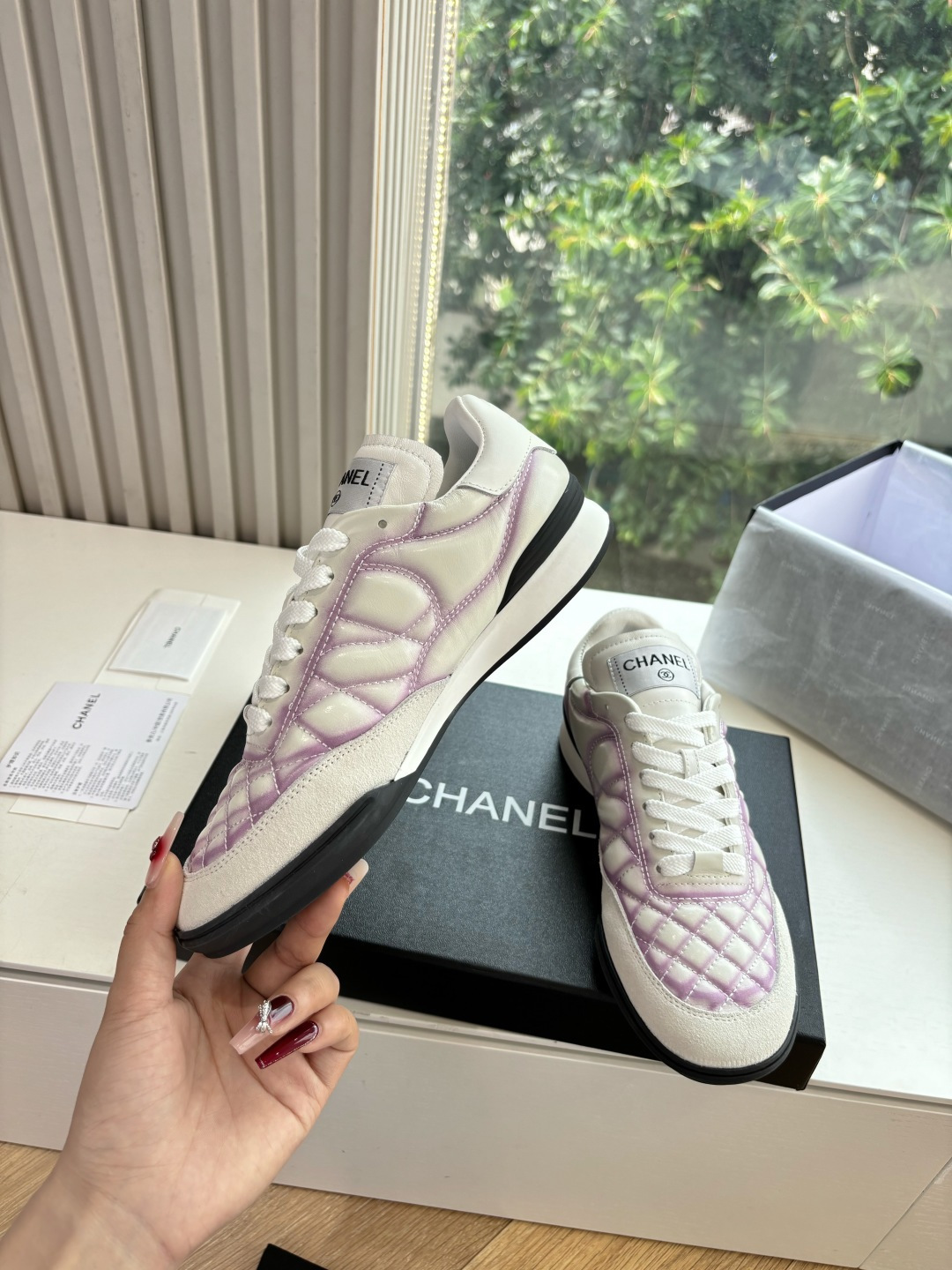 A pair of Chanel white and purple quilted leather sneakers with CC logo displayed in a box - Hình 4