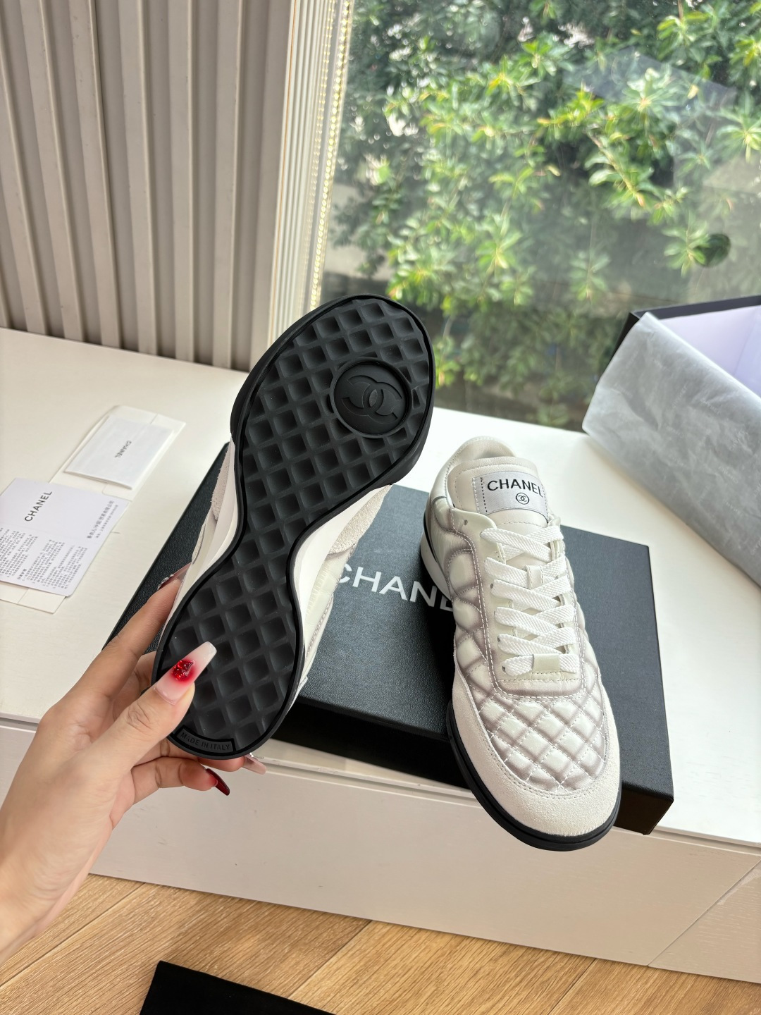 A pair of premium Chanel white quilted sneakers with grey shadow detailing and interlocking CC logo, displayed in their original black box. - Hình 6