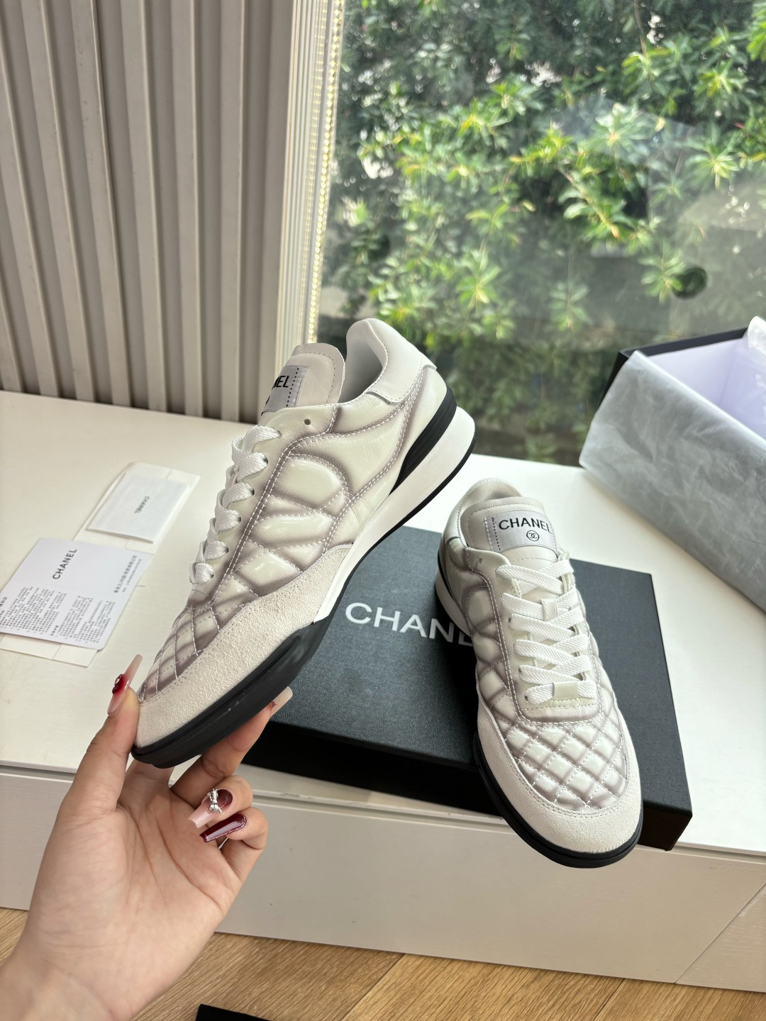 A pair of premium Chanel white quilted sneakers with grey shadow detailing and interlocking CC logo, displayed in their original black box. - Hình 5