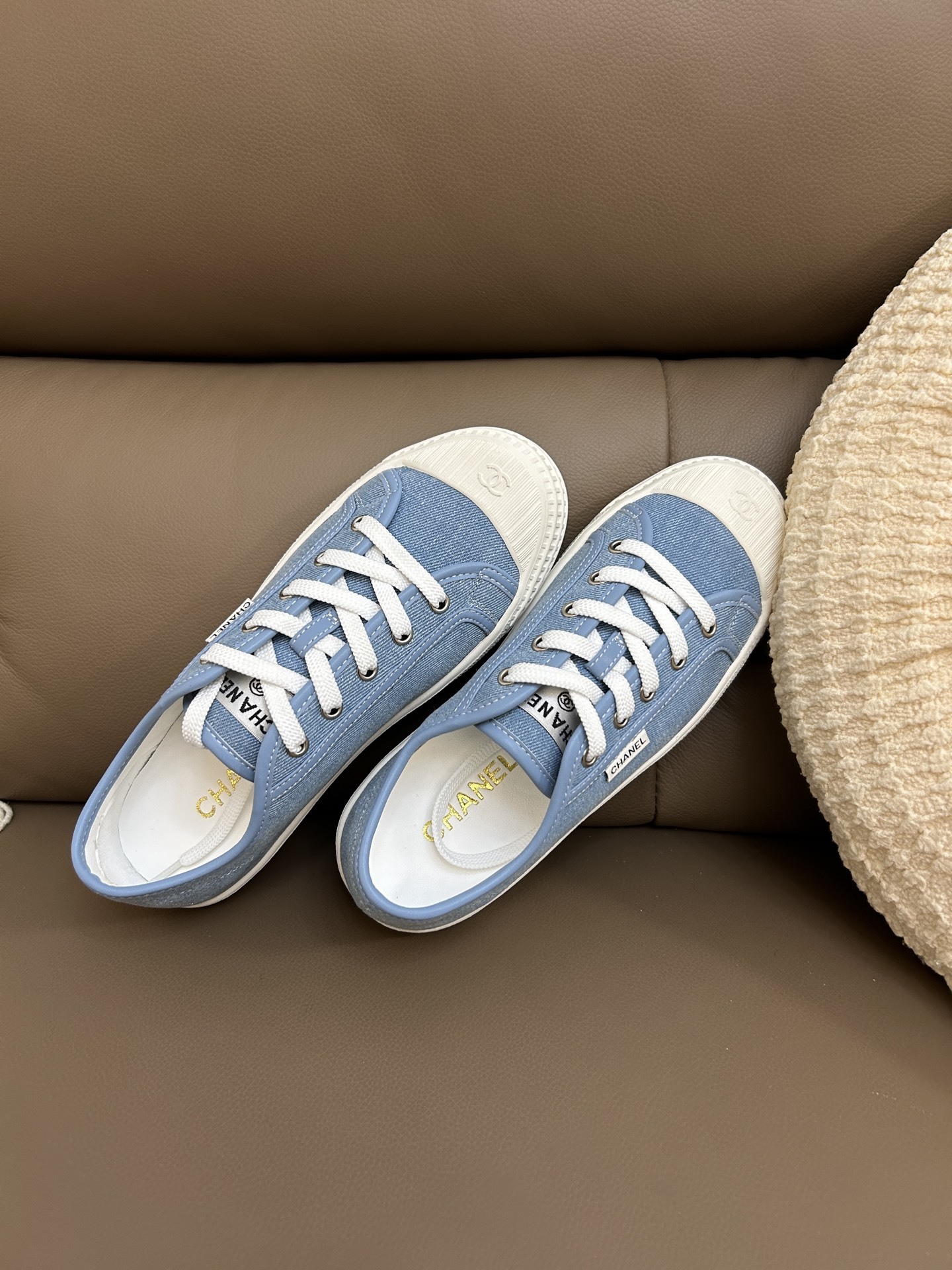 A pair of Chanel light blue denim low-top sneakers with white laces and embossed CC logo on the toe cap. - Hình 4