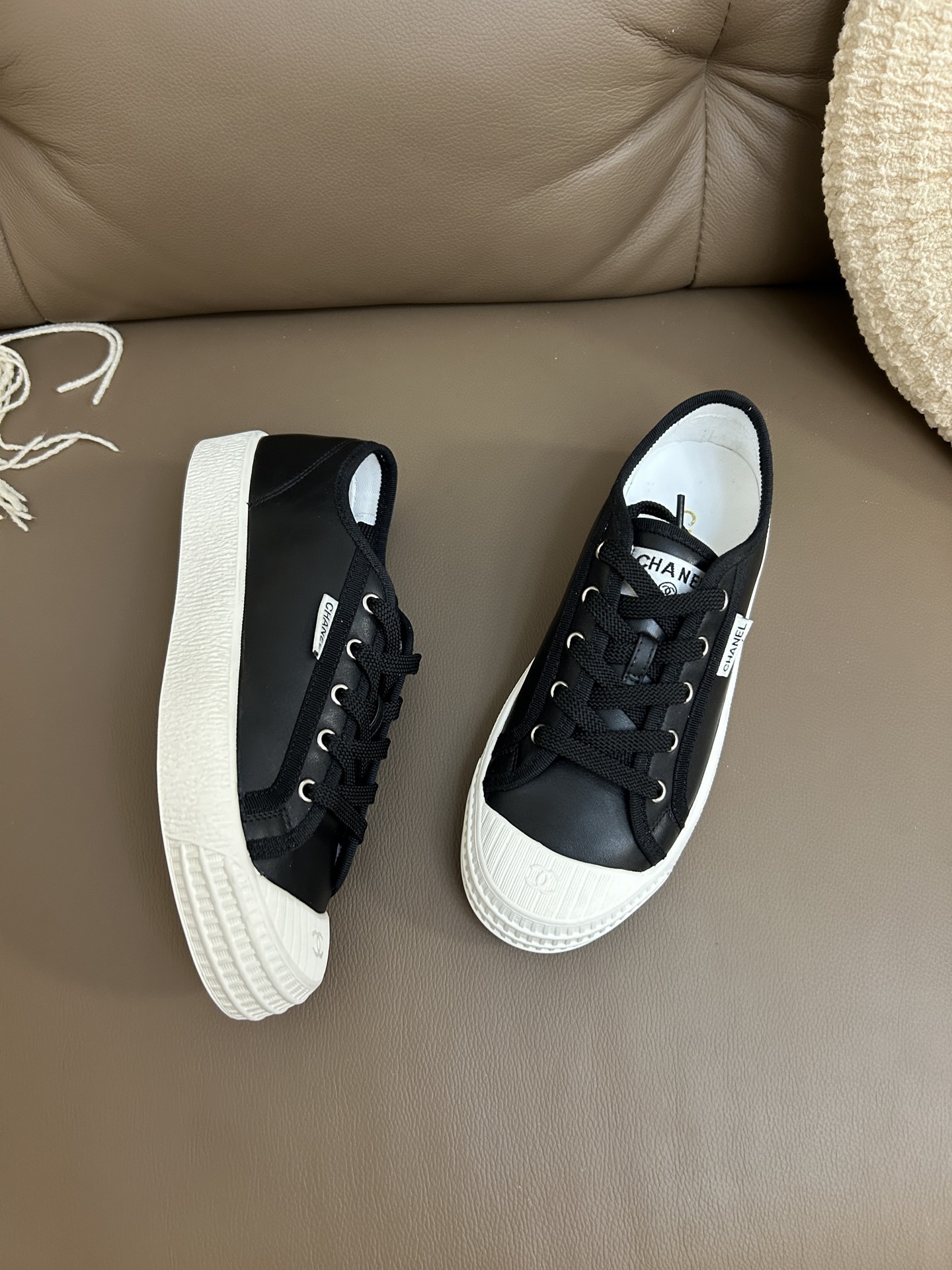 Luxury Chanel black leather sneakers with white rubber soles and embossed CC logo on the toe cap. - Hình 2