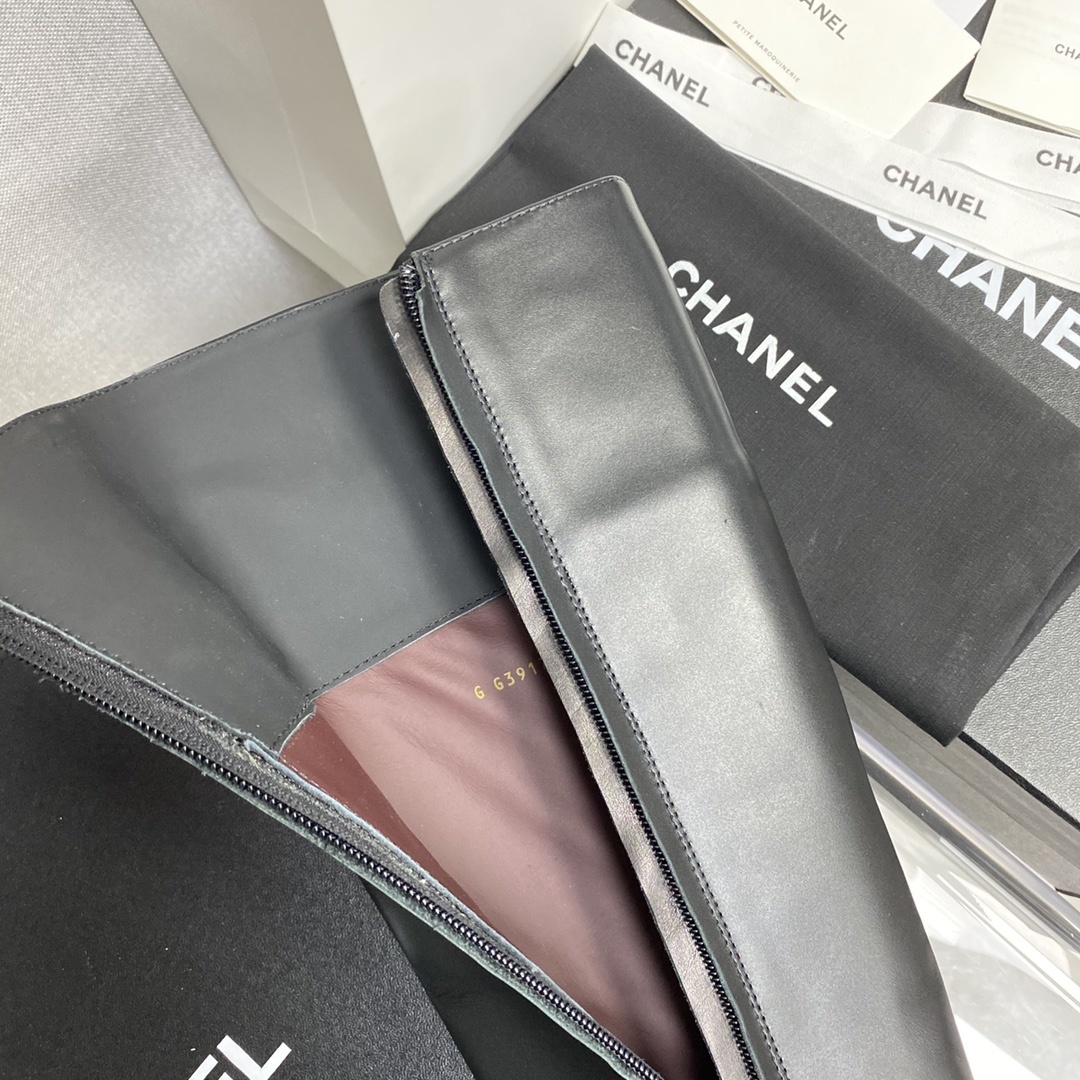 Pair of black leather knee-high boots with gold chain detail on a black designer box - Hình 8