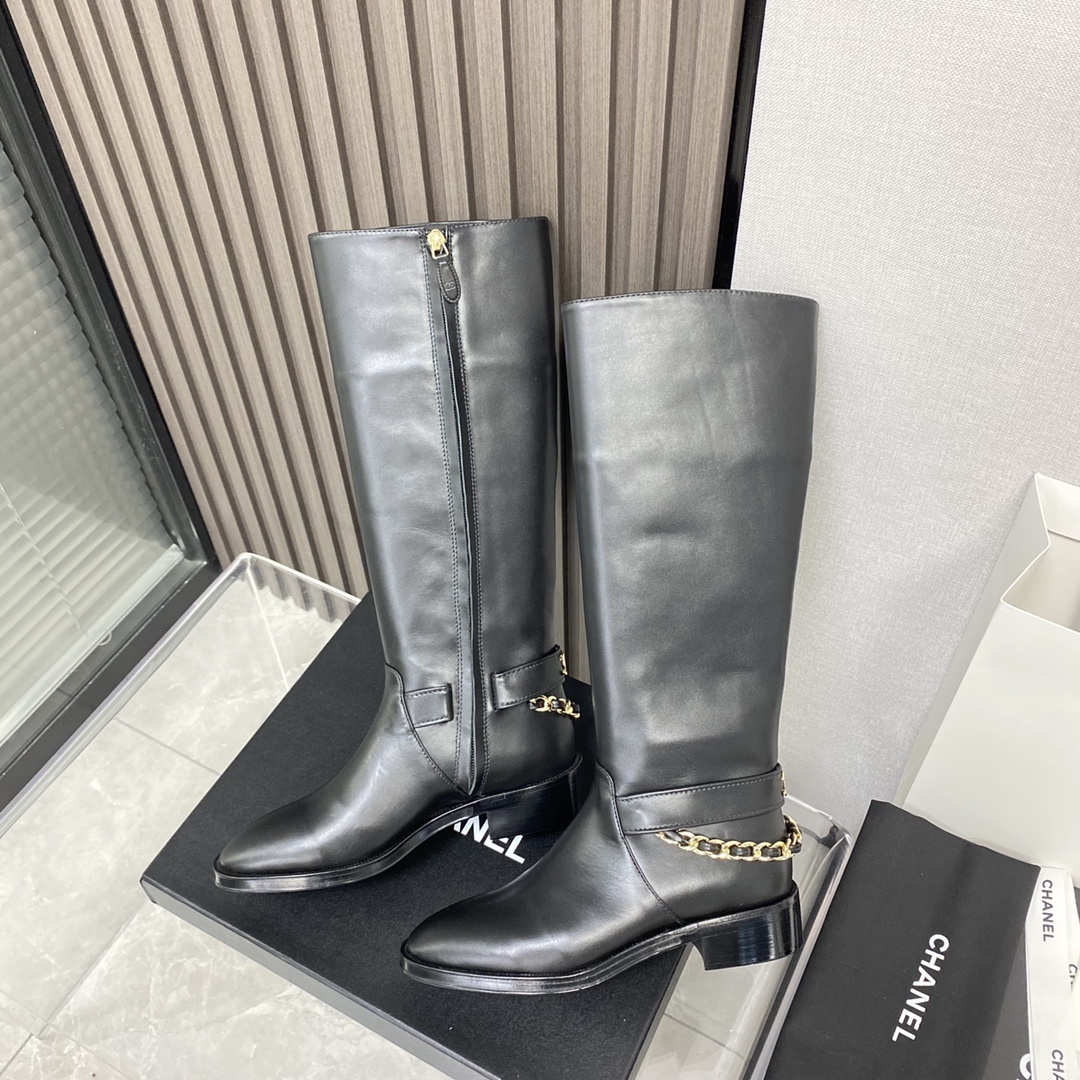 Pair of black leather knee-high boots with gold chain detail on a black designer box - Hình 6