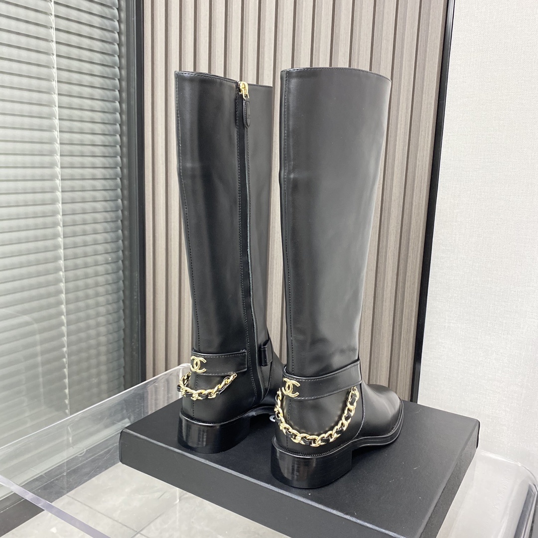 Pair of black leather knee-high boots with gold chain detail on a black designer box - Hình 5