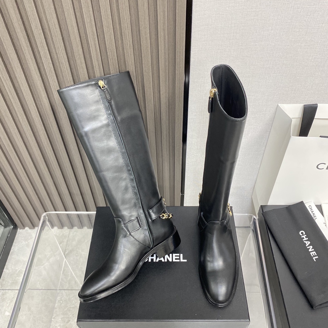 Pair of black leather knee-high boots with gold chain detail on a black designer box - Hình 4