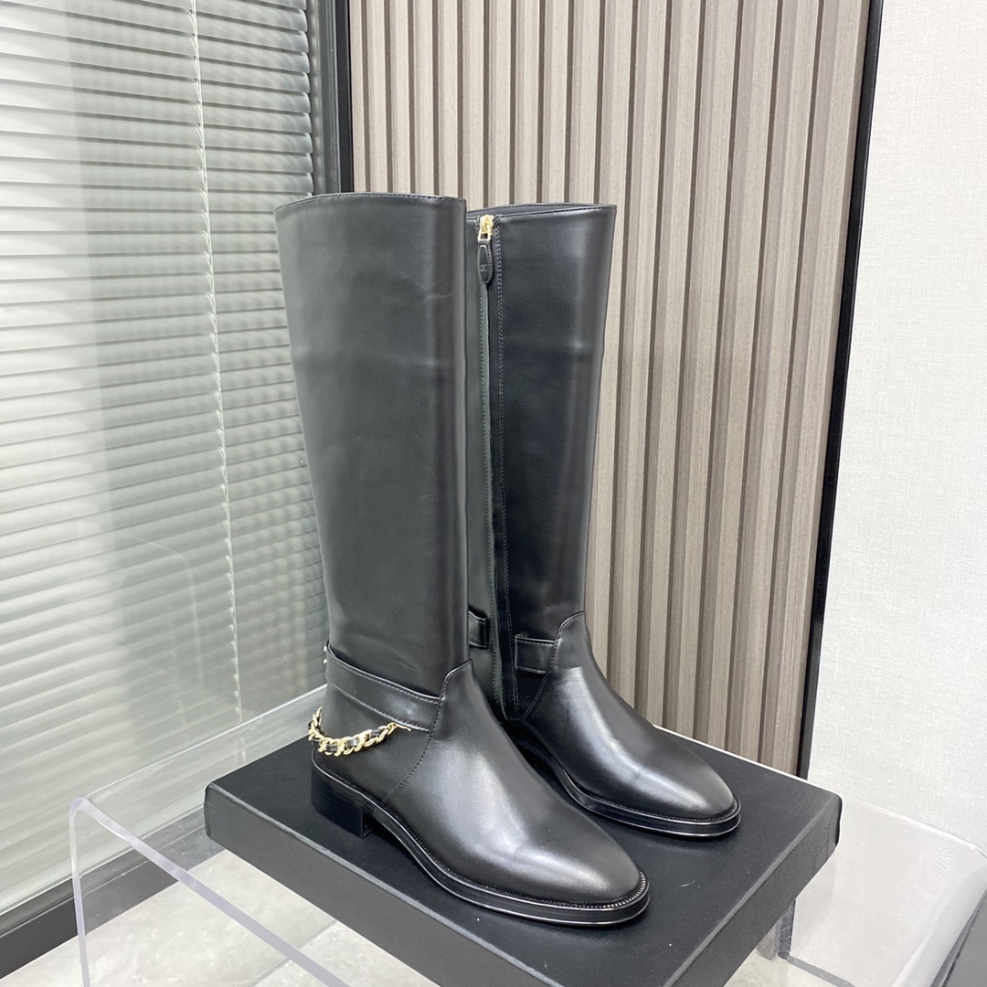 Pair of black leather knee-high boots with gold chain detail on a black designer box - Hình 3