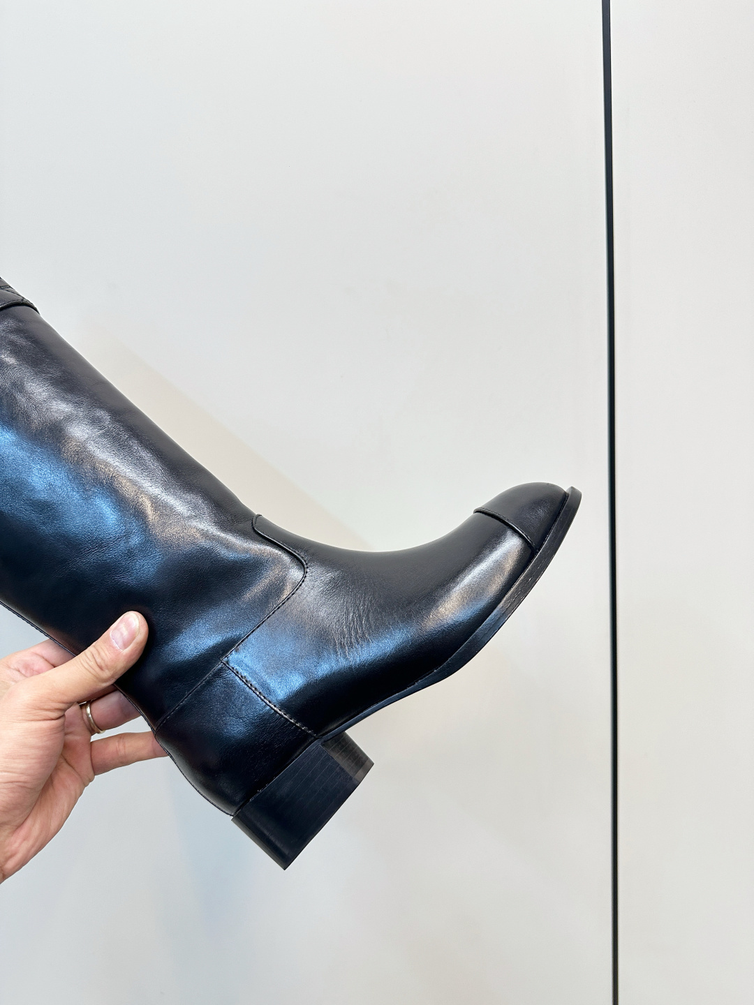 Pair of Chanel black quilted leather knee-high boots with embossed CC logo on a wooden surface. - Hình 7