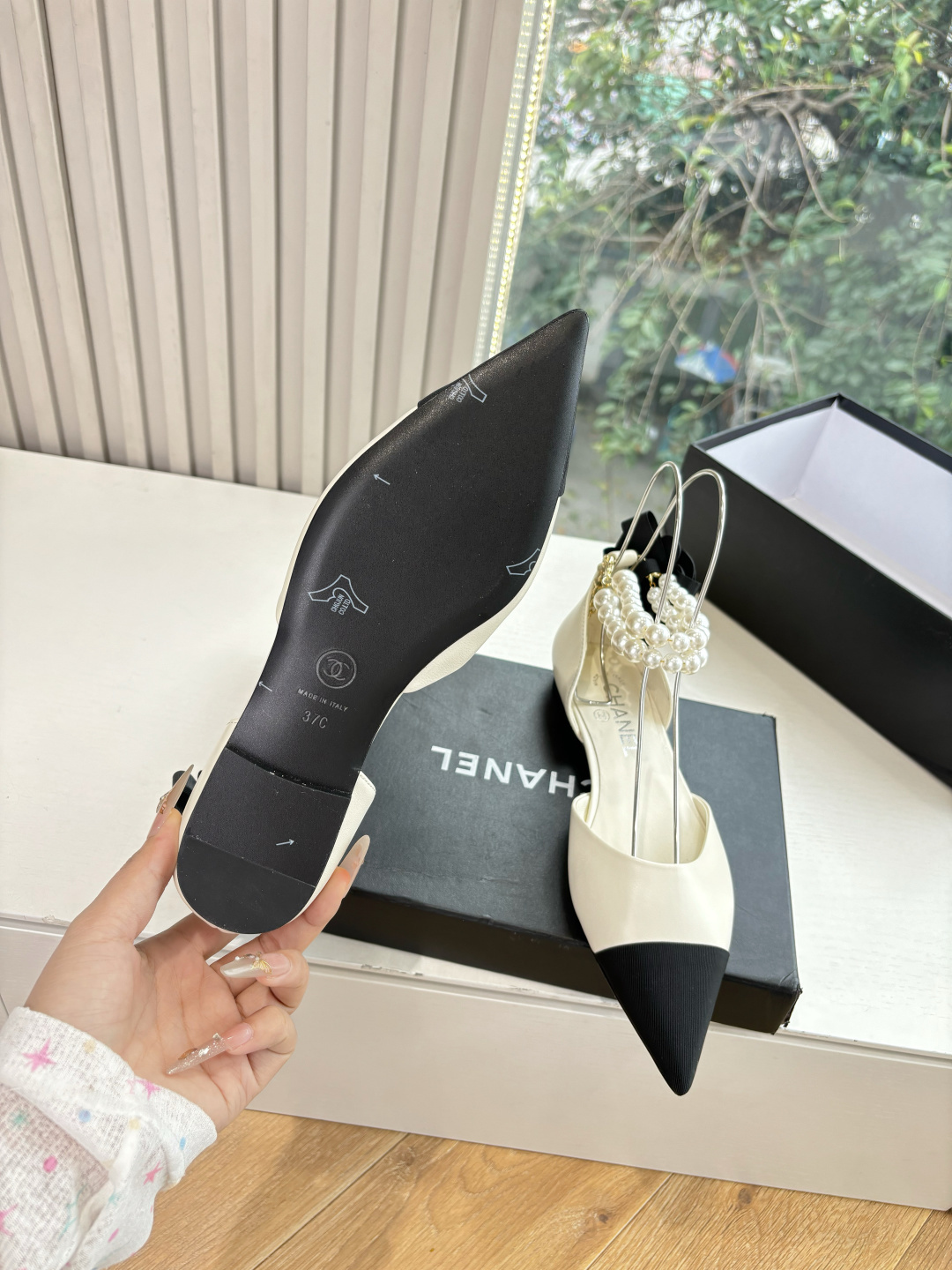 Pair of Chanel ivory leather pointed-toe flats with black cap-toe, pearl ankle straps, and black camellia flower detail on the heel. - Hình 6