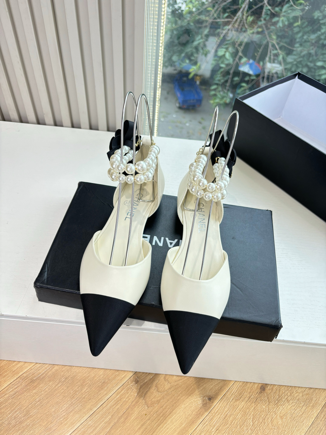 Pair of Chanel ivory leather pointed-toe flats with black cap-toe, pearl ankle straps, and black camellia flower detail on the heel. - Hình 4