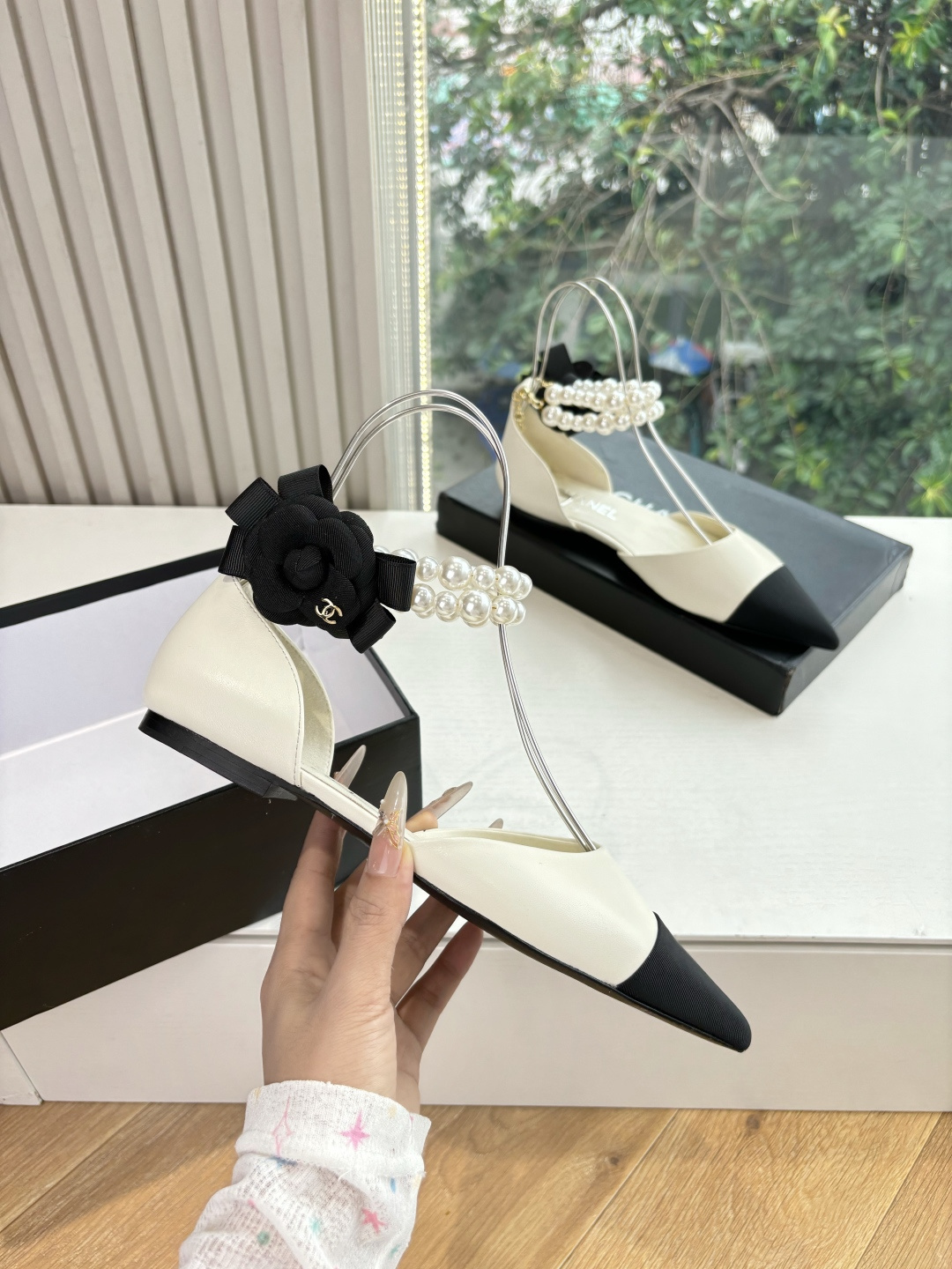 Pair of Chanel ivory leather pointed-toe flats with black cap-toe, pearl ankle straps, and black camellia flower detail on the heel. - Hình 3