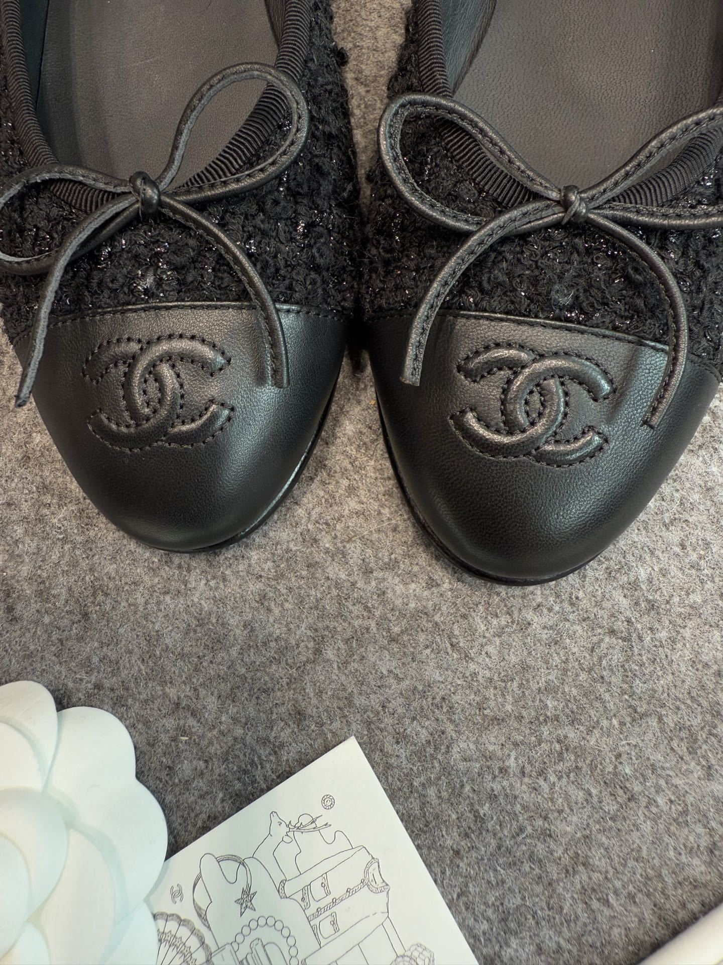 A pair of black Chanel tweed ballerina flats with leather CC logo toe caps and bow details inside a luxury box. - Hình 10