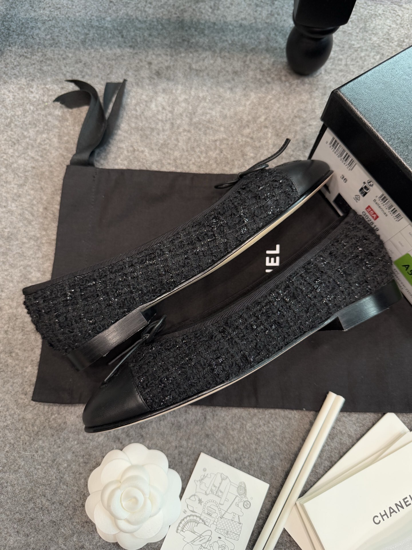 A pair of black Chanel tweed ballerina flats with leather CC logo toe caps and bow details inside a luxury box. - Hình 6