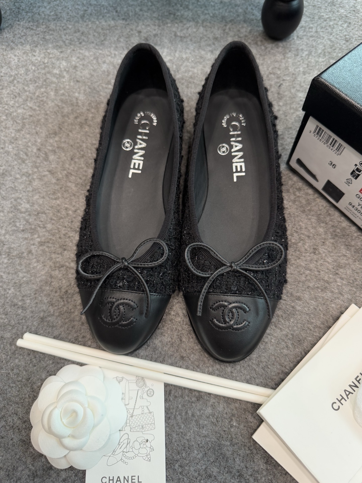 A pair of black Chanel tweed ballerina flats with leather CC logo toe caps and bow details inside a luxury box. - Hình 5