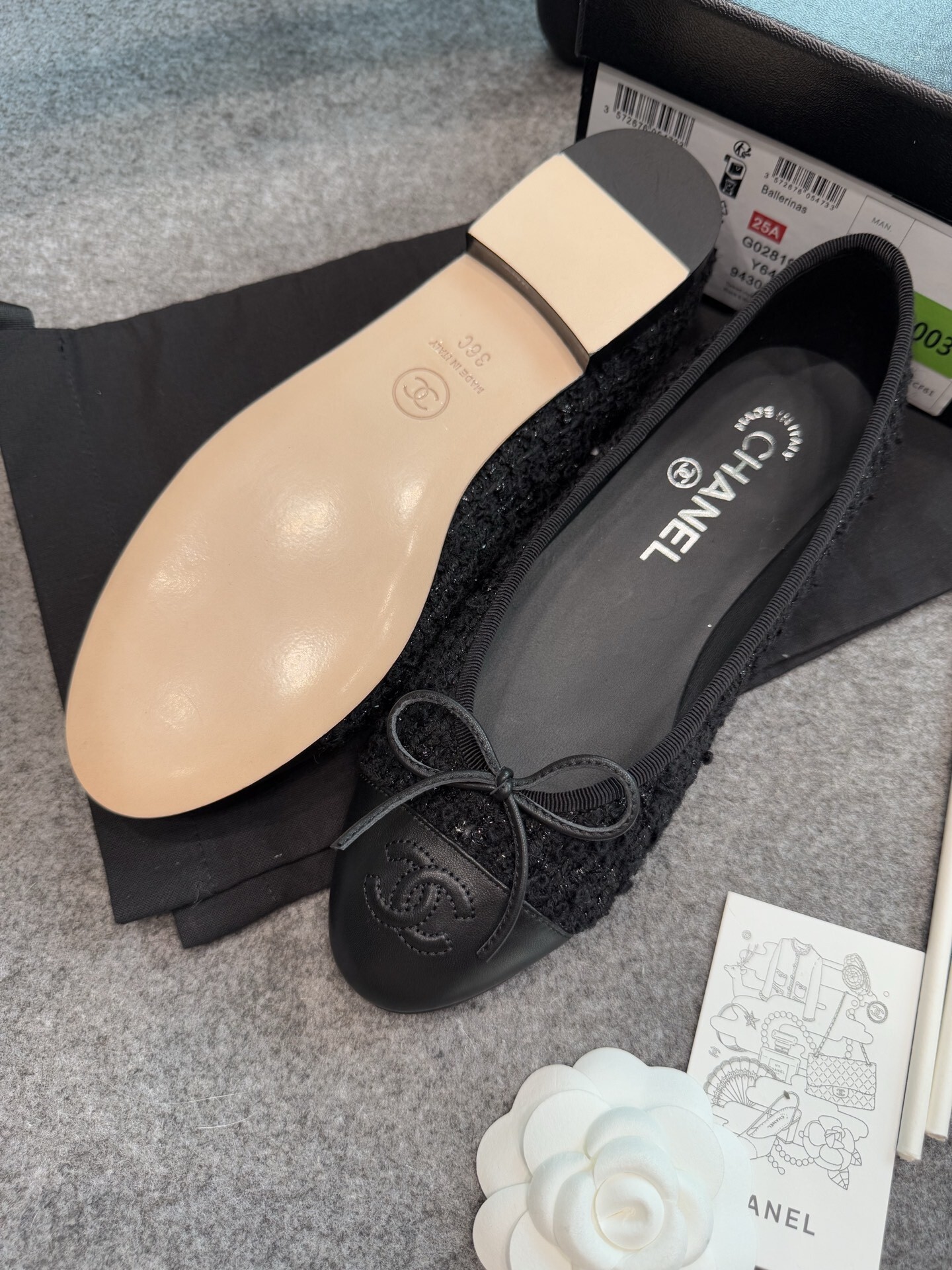 A pair of black Chanel tweed ballerina flats with leather CC logo toe caps and bow details inside a luxury box. - Hình 2