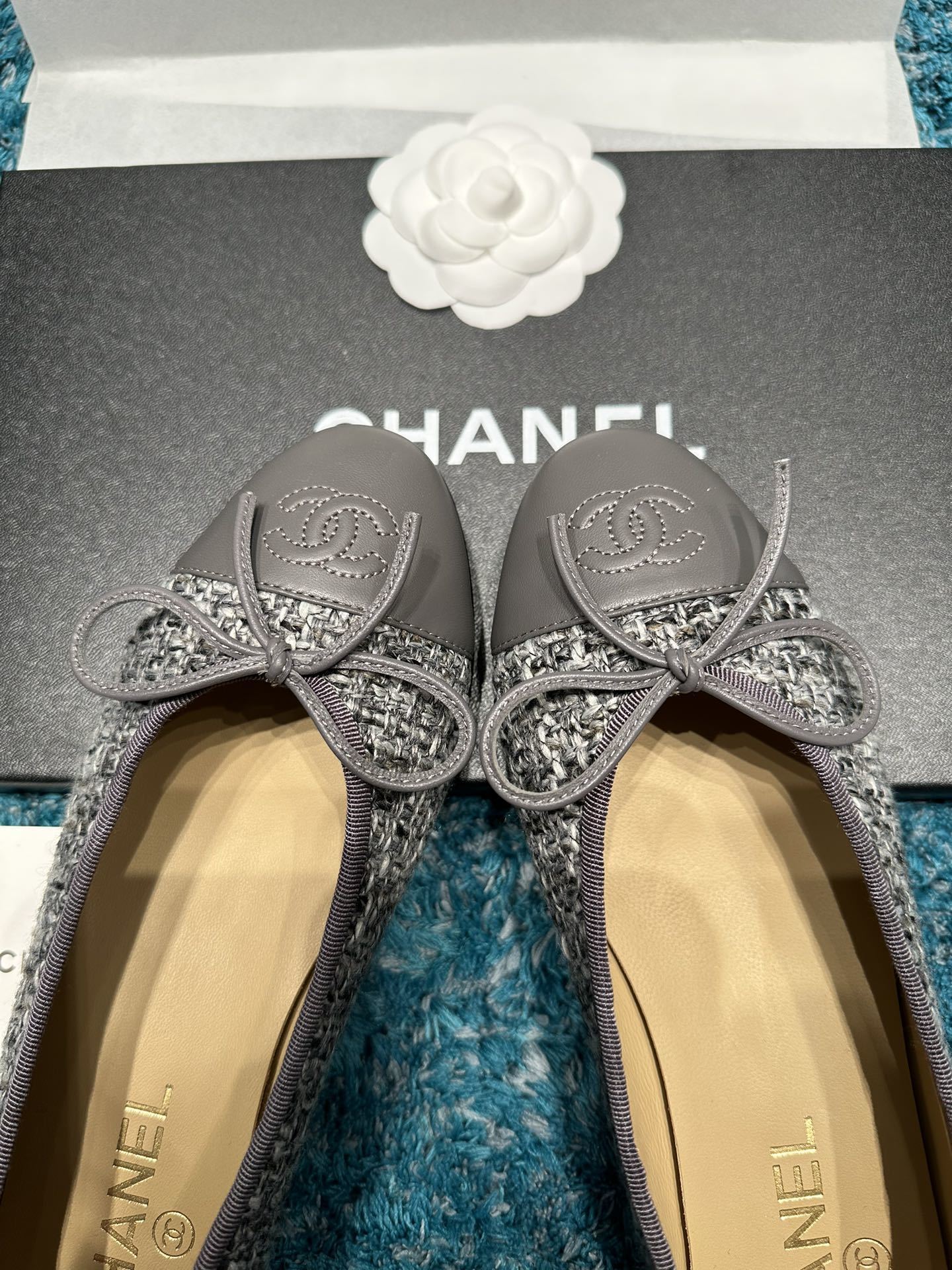 Top view of Chanel grey tweed ballet flats with grey leather toe caps featuring the CC logo and decorative bows in a Chanel box. - Hình 4