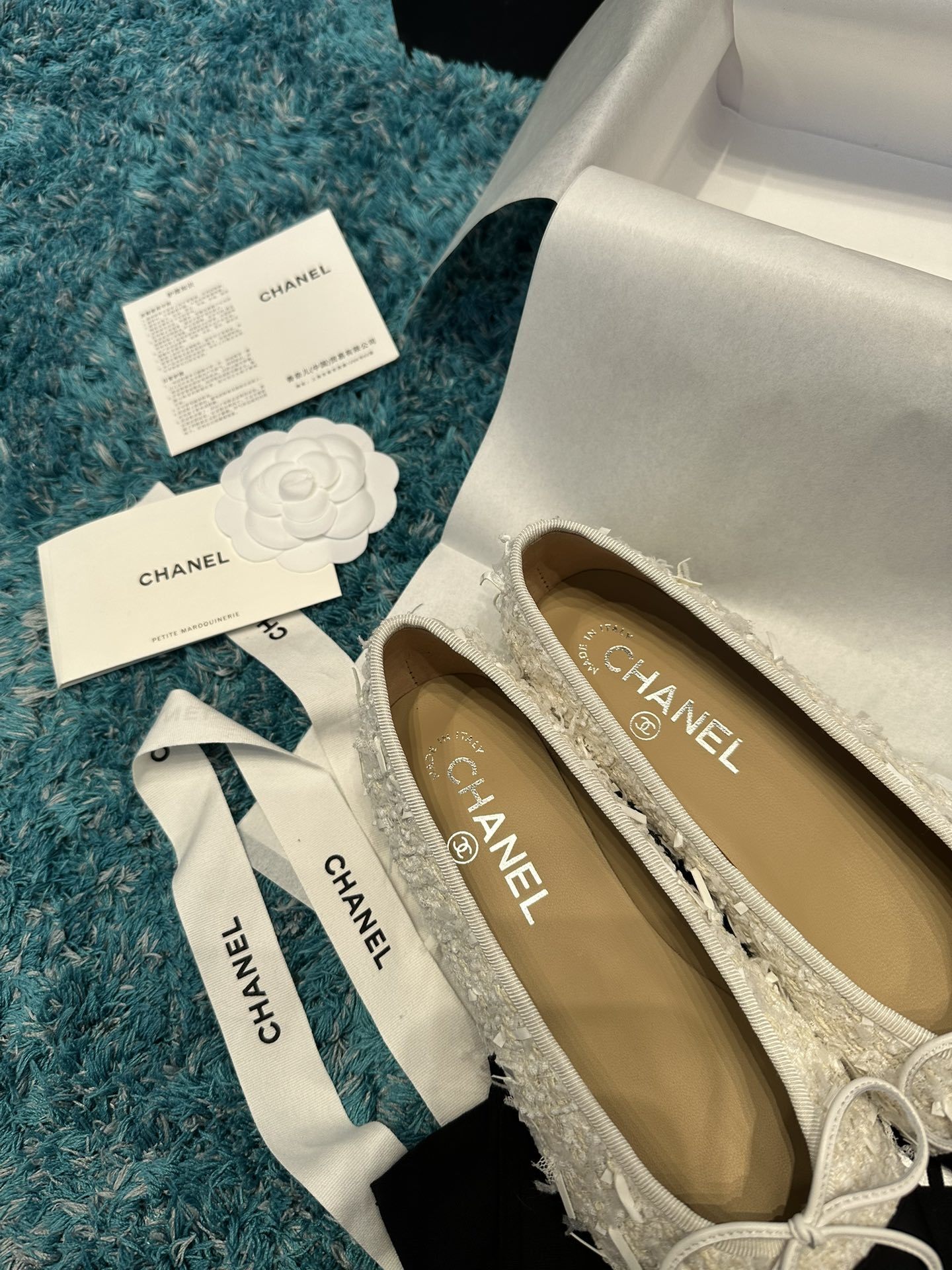 A pair of Chanel white tweed ballet flats with black toe caps and white bows, presented in a Chanel box with branded ribbons. - Hình 7
