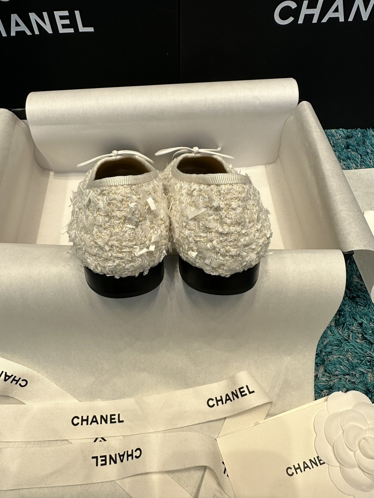 A pair of Chanel white tweed ballet flats with black toe caps and white bows, presented in a Chanel box with branded ribbons. - Hình 6