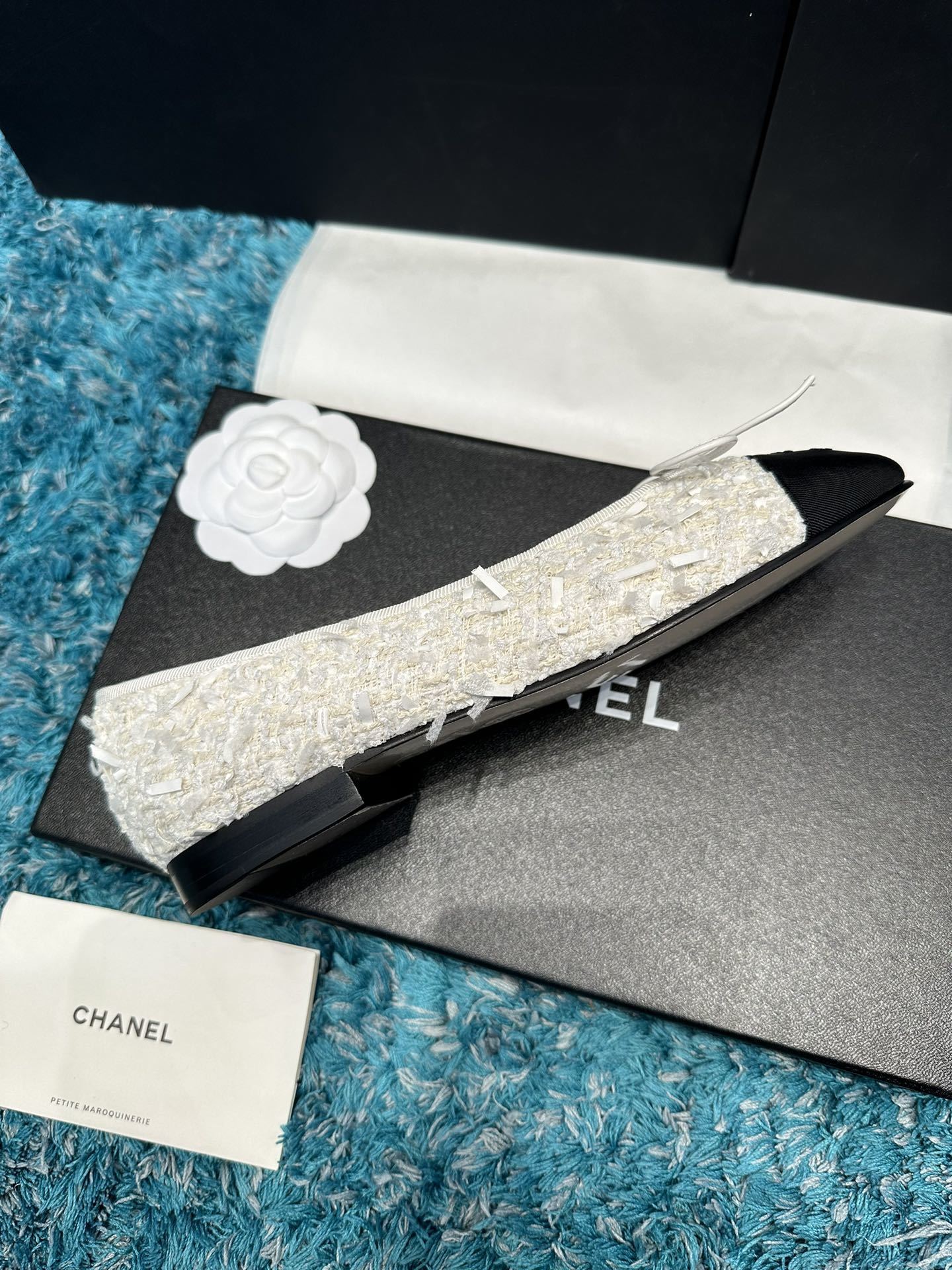 A pair of Chanel white tweed ballet flats with black toe caps and white bows, presented in a Chanel box with branded ribbons. - Hình 4
