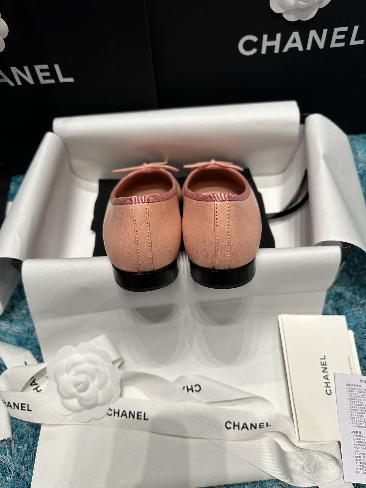 A pair of pink Chanel ballerina flats with black toe caps and bow details sitting in original packaging. - Hình 6