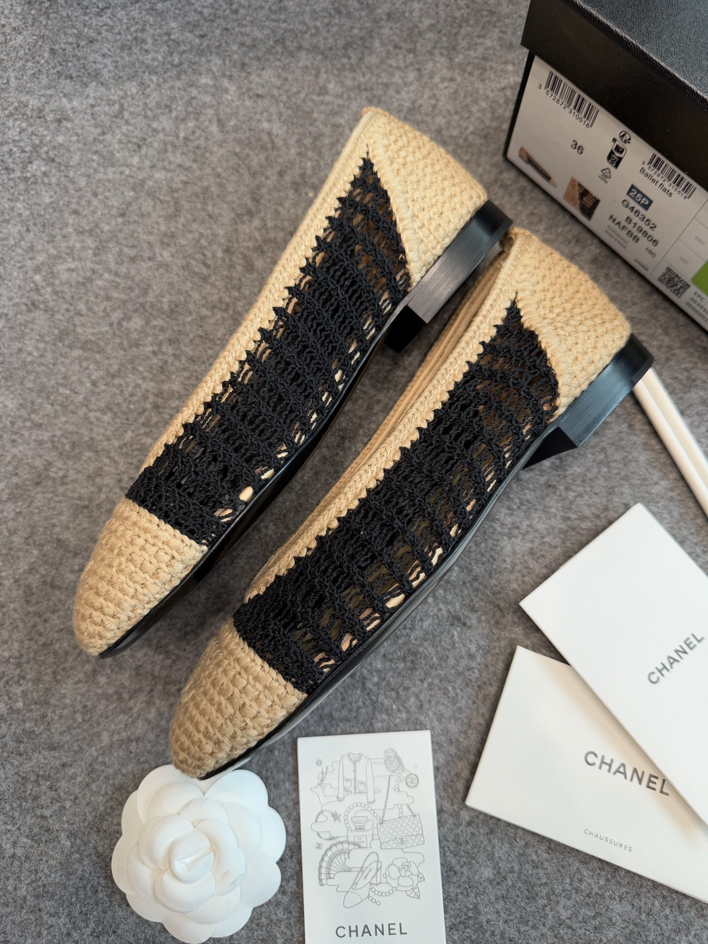 A pair of authentic Chanel beige and black crochet ballet flats with CC logo on the toe, shown with original packaging and camellia flower. - Hình 4