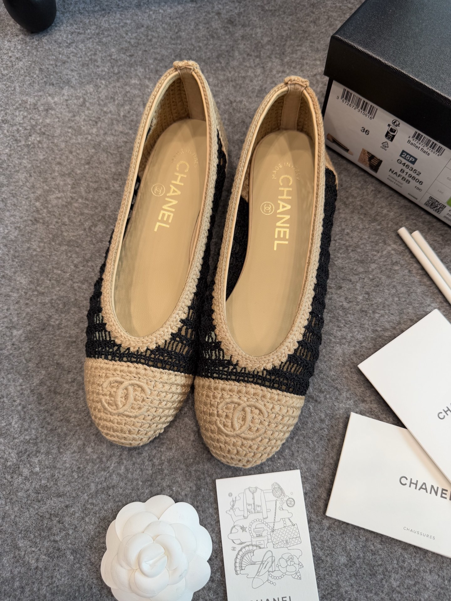 A pair of authentic Chanel beige and black crochet ballet flats with CC logo on the toe, shown with original packaging and camellia flower. - Hình 3
