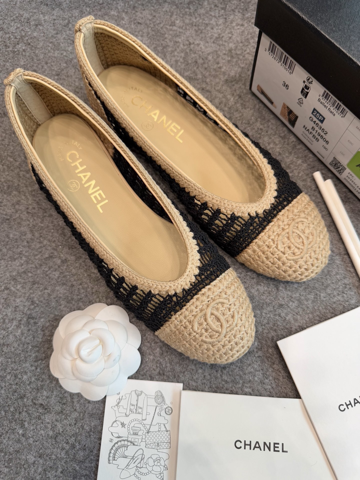 A pair of authentic Chanel beige and black crochet ballet flats with CC logo on the toe, shown with original packaging and camellia flower. - Hình 2