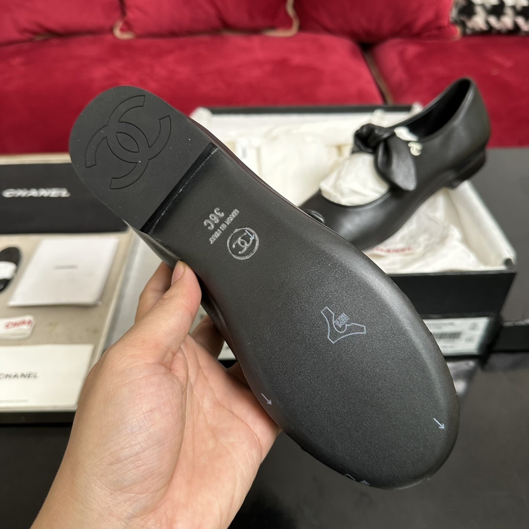 Pair of black Chanel Mary Jane leather flats with a knotted strap and cap toe in original packaging. - Hình 9