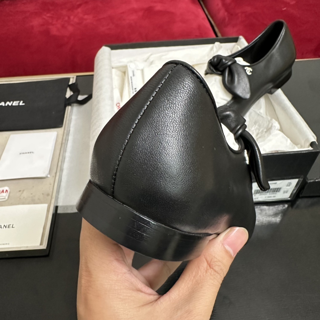 Pair of black Chanel Mary Jane leather flats with a knotted strap and cap toe in original packaging. - Hình 8