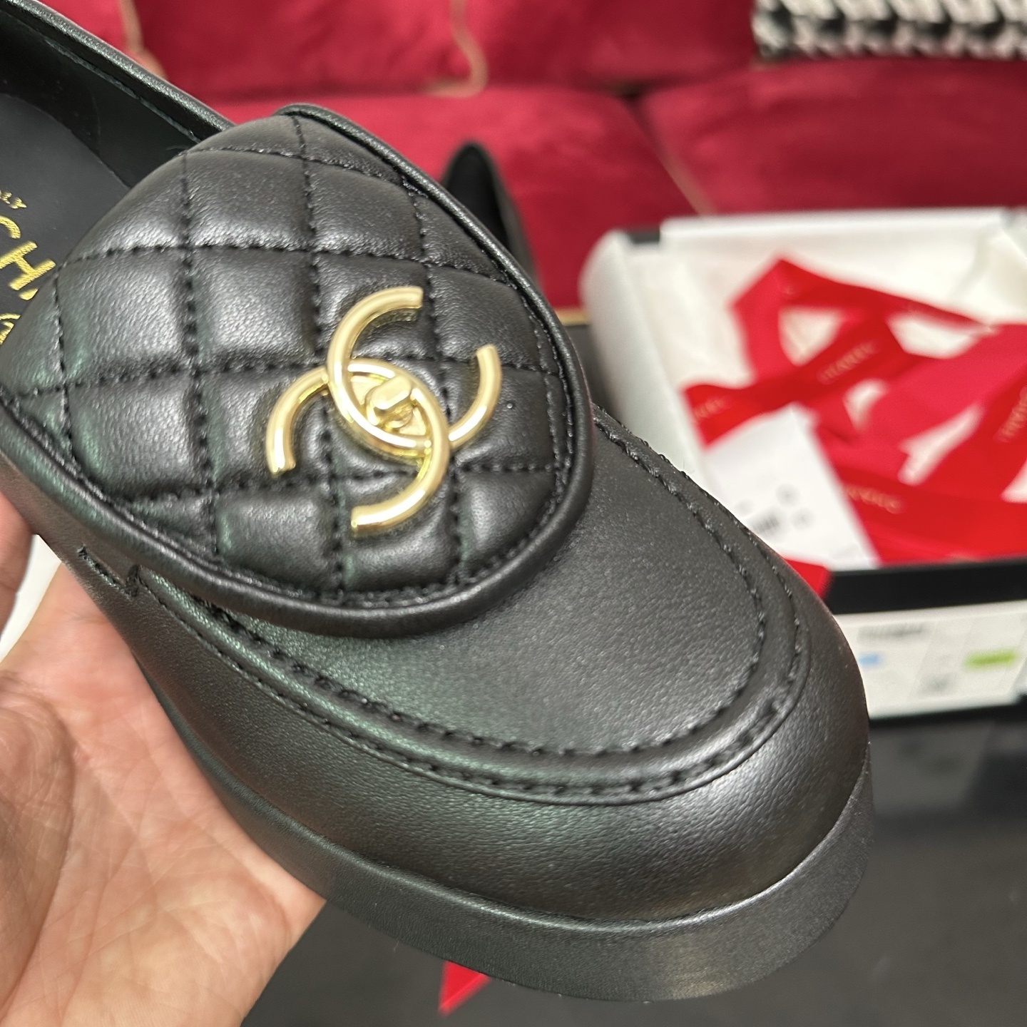 Chanel black quilted leather platform loafers with gold CC logo hardware on a display table with original packaging. - Hình 6
