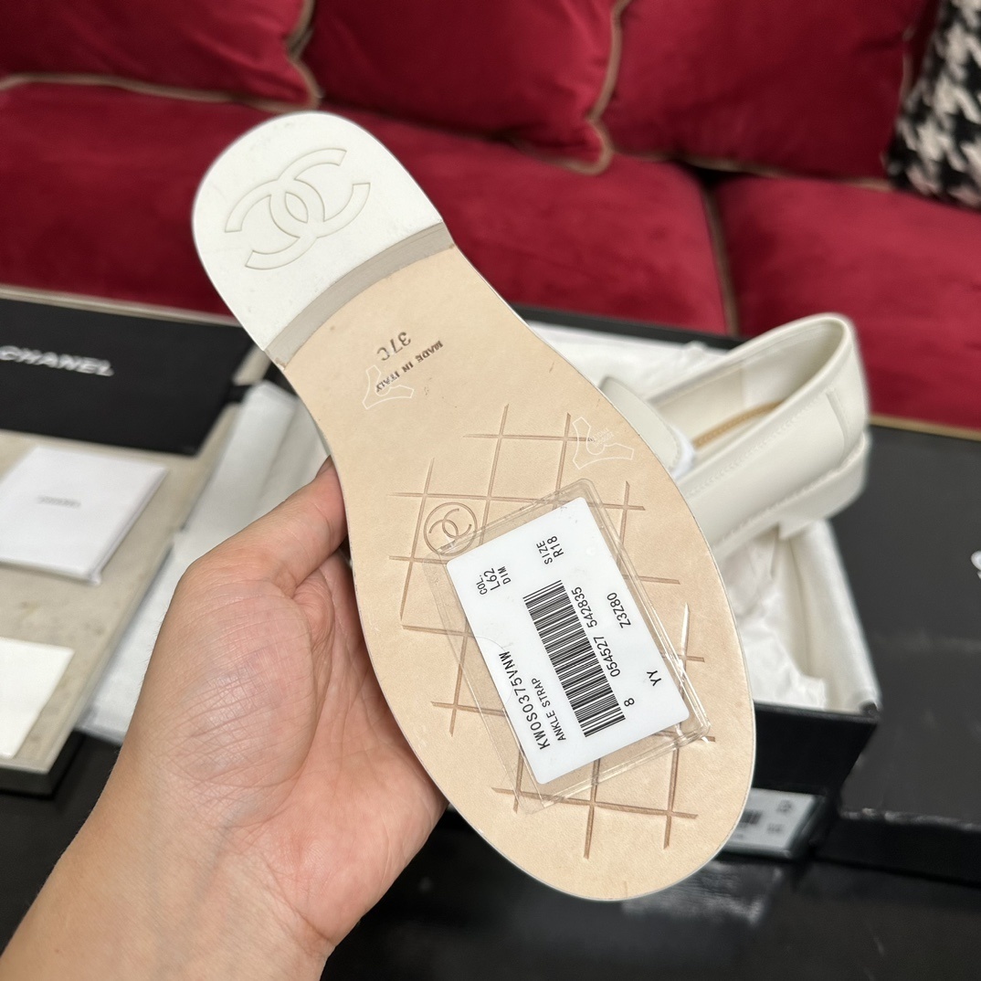 A pair of luxury Chanel white leather loafers with gold CC logo hardware displayed in their original black and white box with authenticity cards. - Hình 9