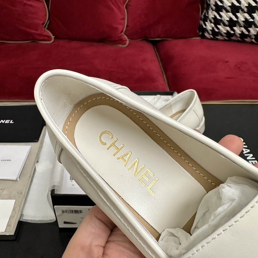 A pair of luxury Chanel white leather loafers with gold CC logo hardware displayed in their original black and white box with authenticity cards. - Hình 7