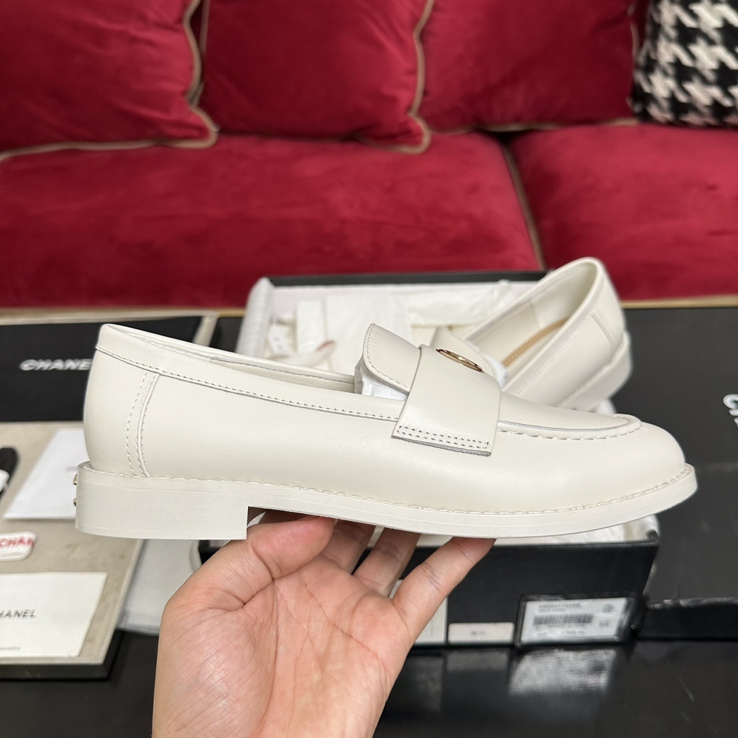 A pair of luxury Chanel white leather loafers with gold CC logo hardware displayed in their original black and white box with authenticity cards. - Hình 5