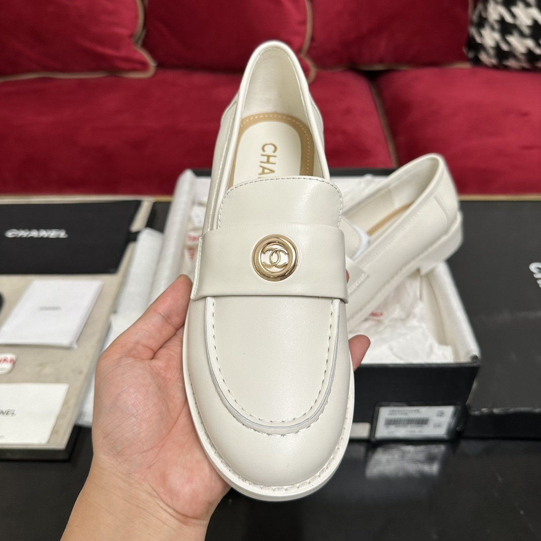 A pair of luxury Chanel white leather loafers with gold CC logo hardware displayed in their original black and white box with authenticity cards. - Hình 3
