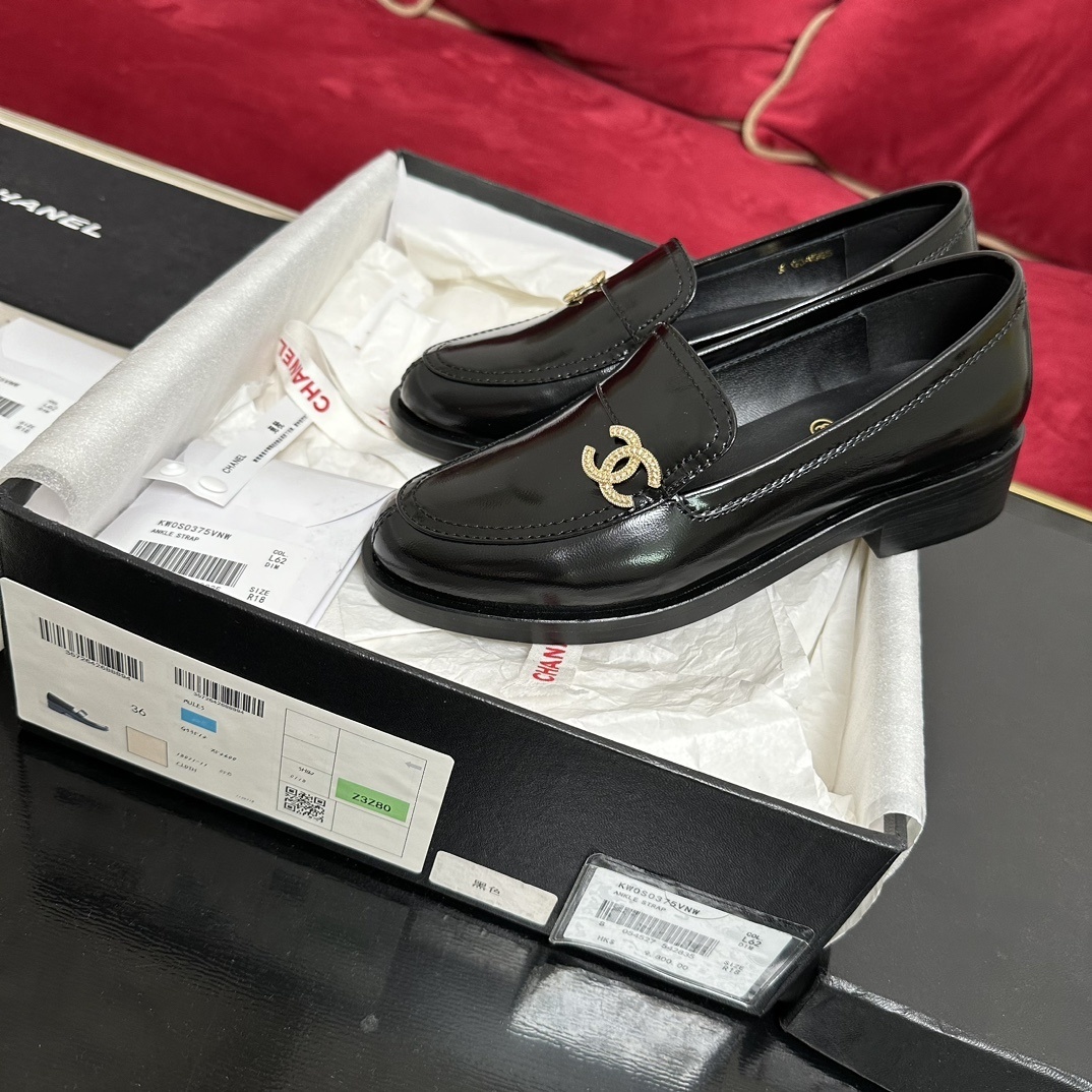 Luxury black Chanel leather loafers with a signature gold CC logo sitting inside their original black designer box. - Hình 2