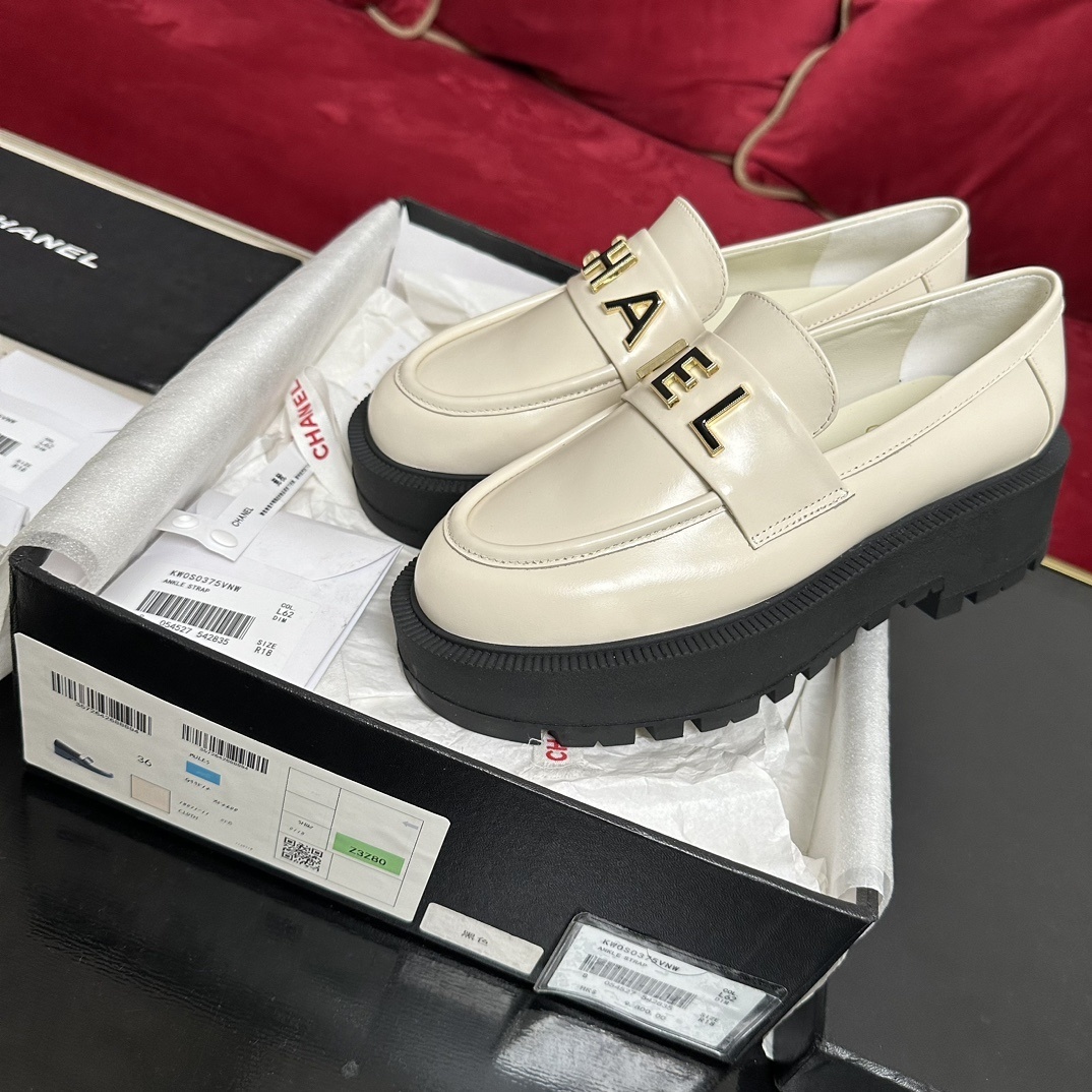 Luxury Chanel cream leather loafers with chunky black platform soles and gold metal logo lettering on the front strap. - Hình 2
