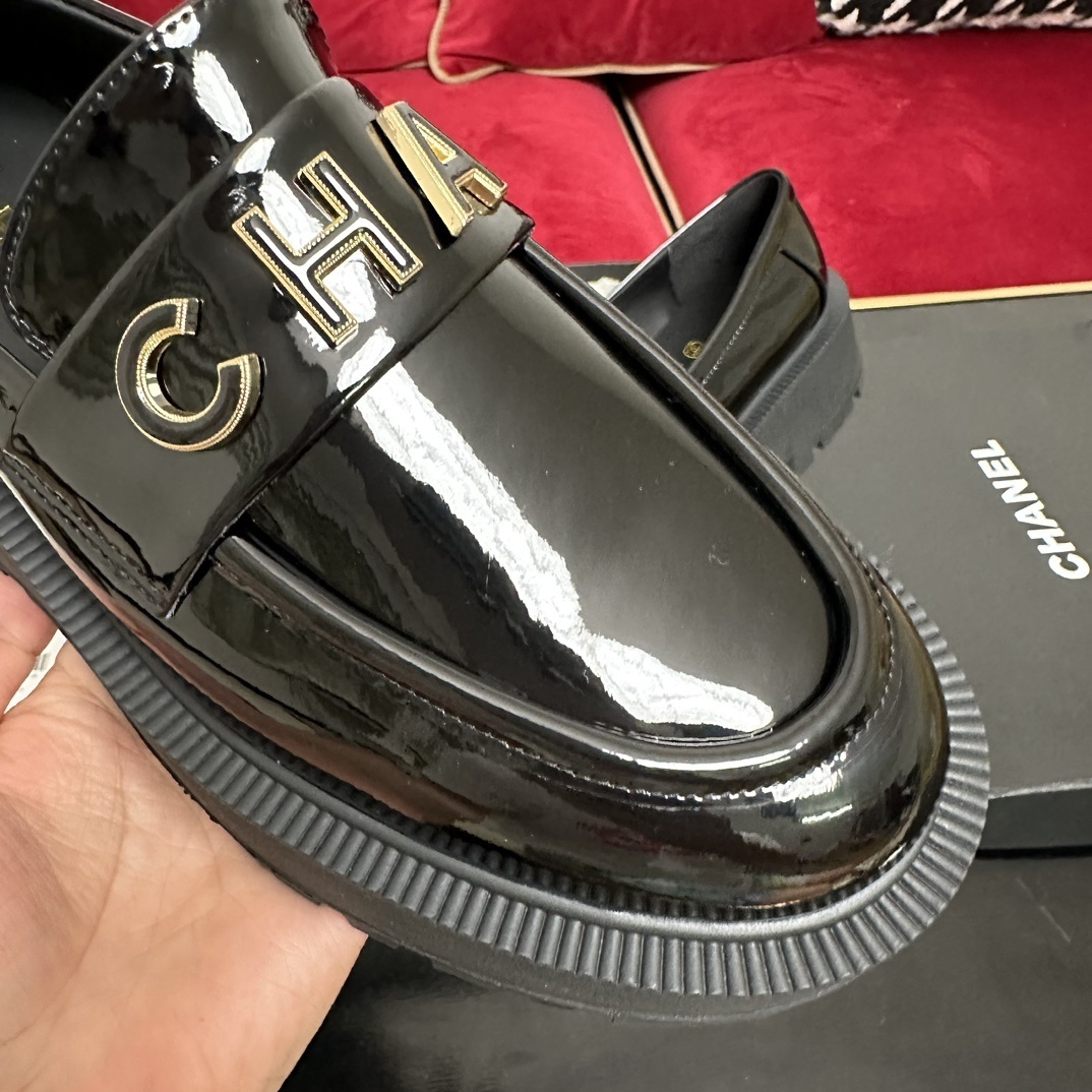 High-end Chanel black patent leather platform loafers with gold-tone CHANEL metal logo on the strap, displayed with original packaging. - Hình 6