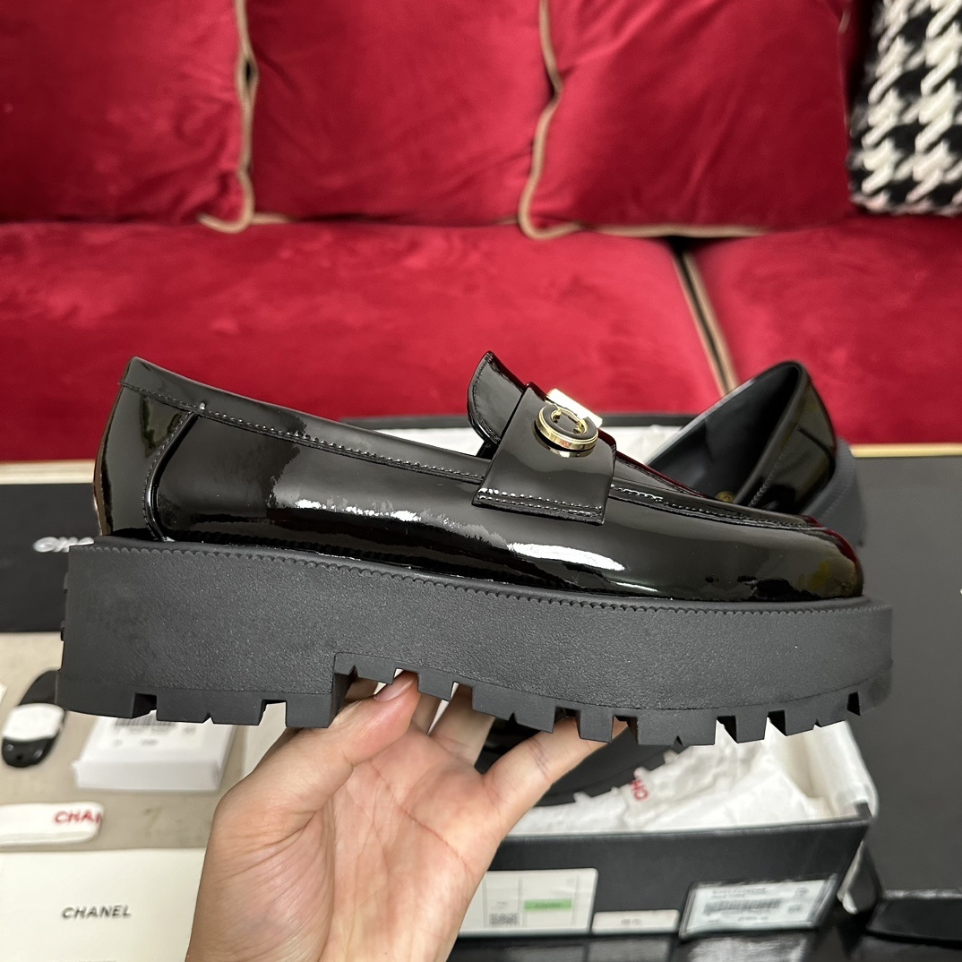 High-end Chanel black patent leather platform loafers with gold-tone CHANEL metal logo on the strap, displayed with original packaging. - Hình 5