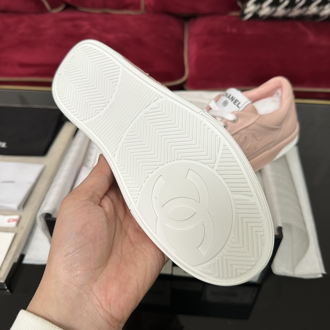 A pair of pink Chanel leather low-top sneakers with white laces and embossed CC logo sitting in their original box with accessories. - Hình 9