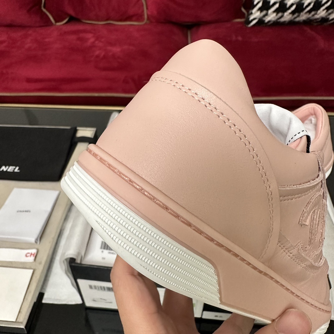 A pair of pink Chanel leather low-top sneakers with white laces and embossed CC logo sitting in their original box with accessories. - Hình 8