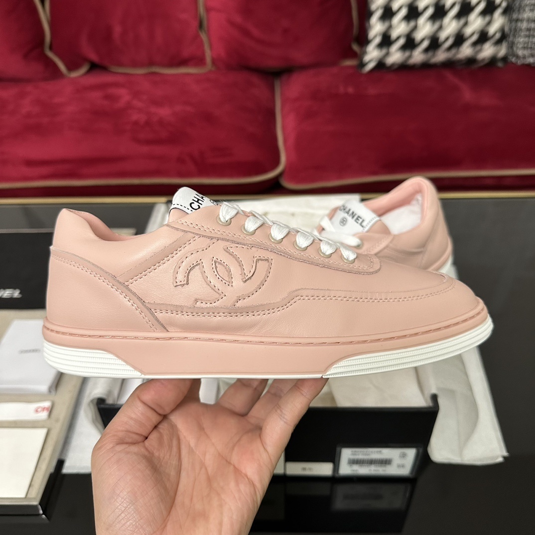 A pair of pink Chanel leather low-top sneakers with white laces and embossed CC logo sitting in their original box with accessories. - Hình 5