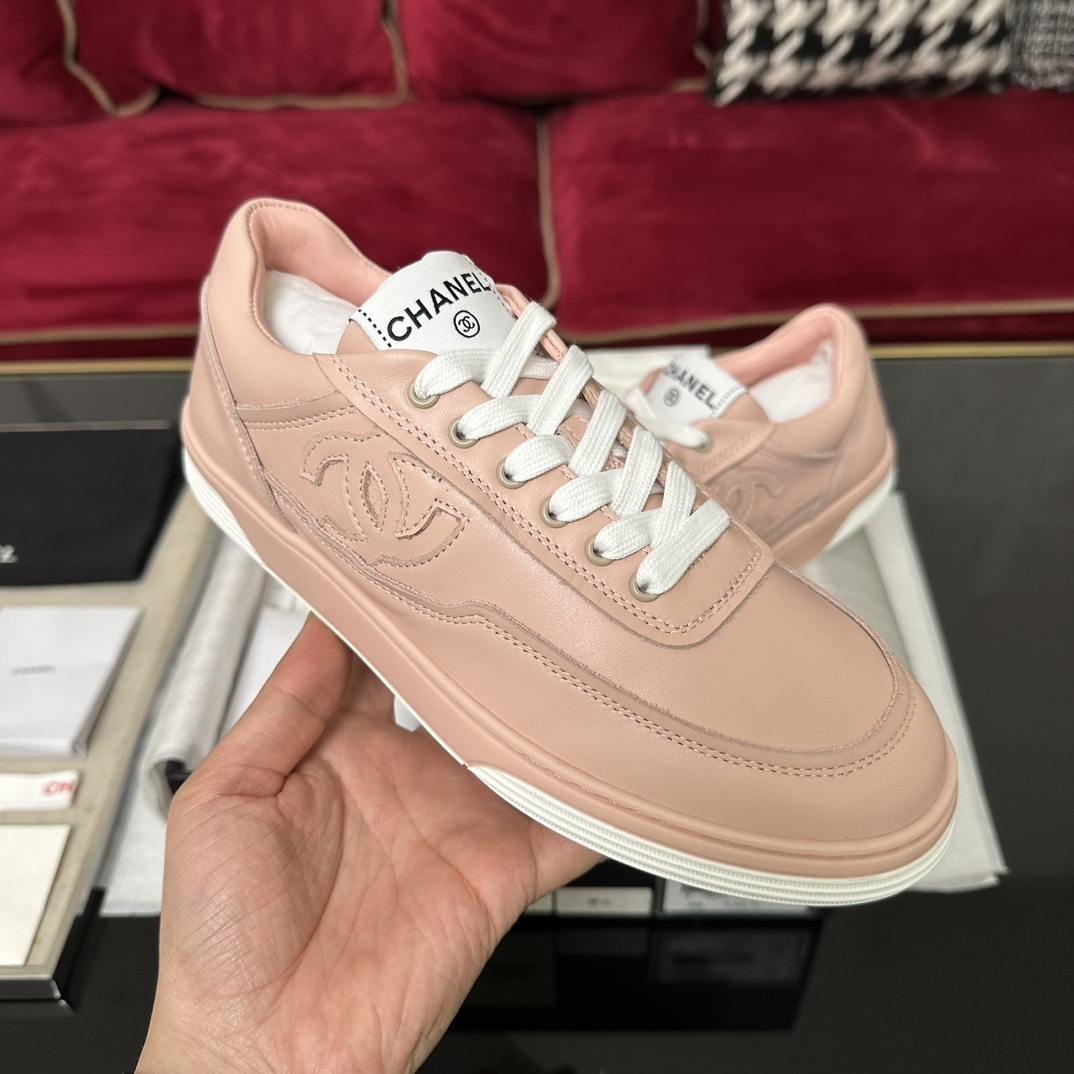 A pair of pink Chanel leather low-top sneakers with white laces and embossed CC logo sitting in their original box with accessories. - Hình 4